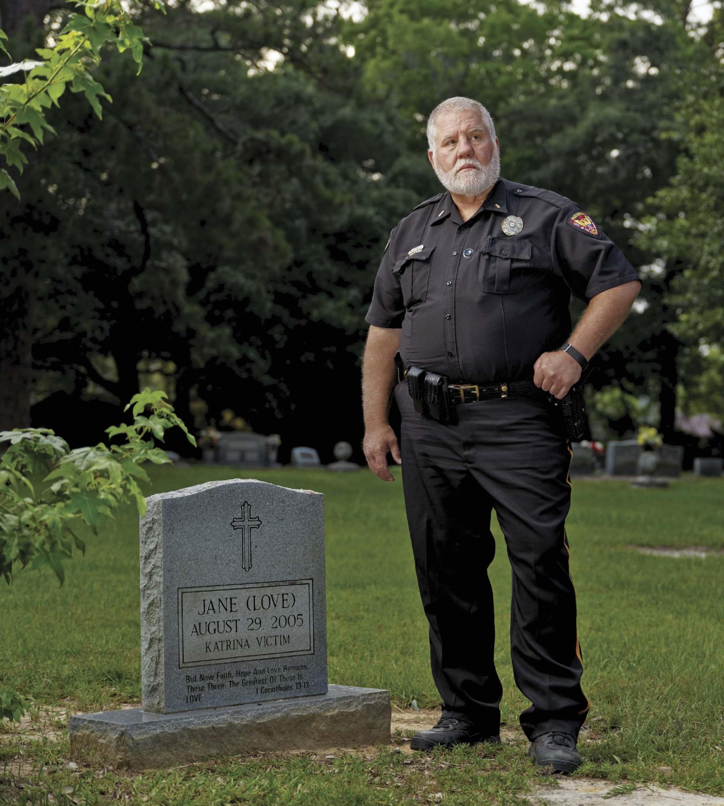 Photo of man standing above gravestone