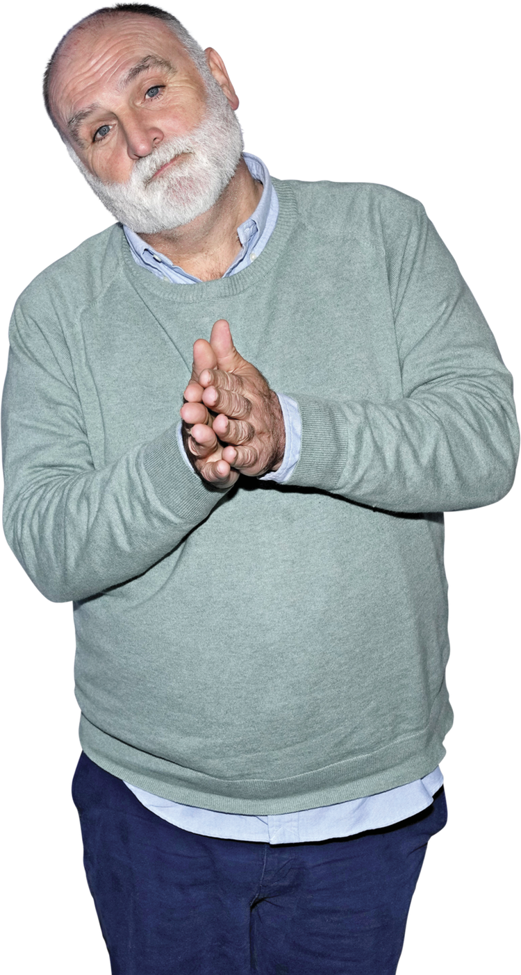 Portrait of José Andrés wearing a light blue sweater, navy blue pants and smiling at the camera