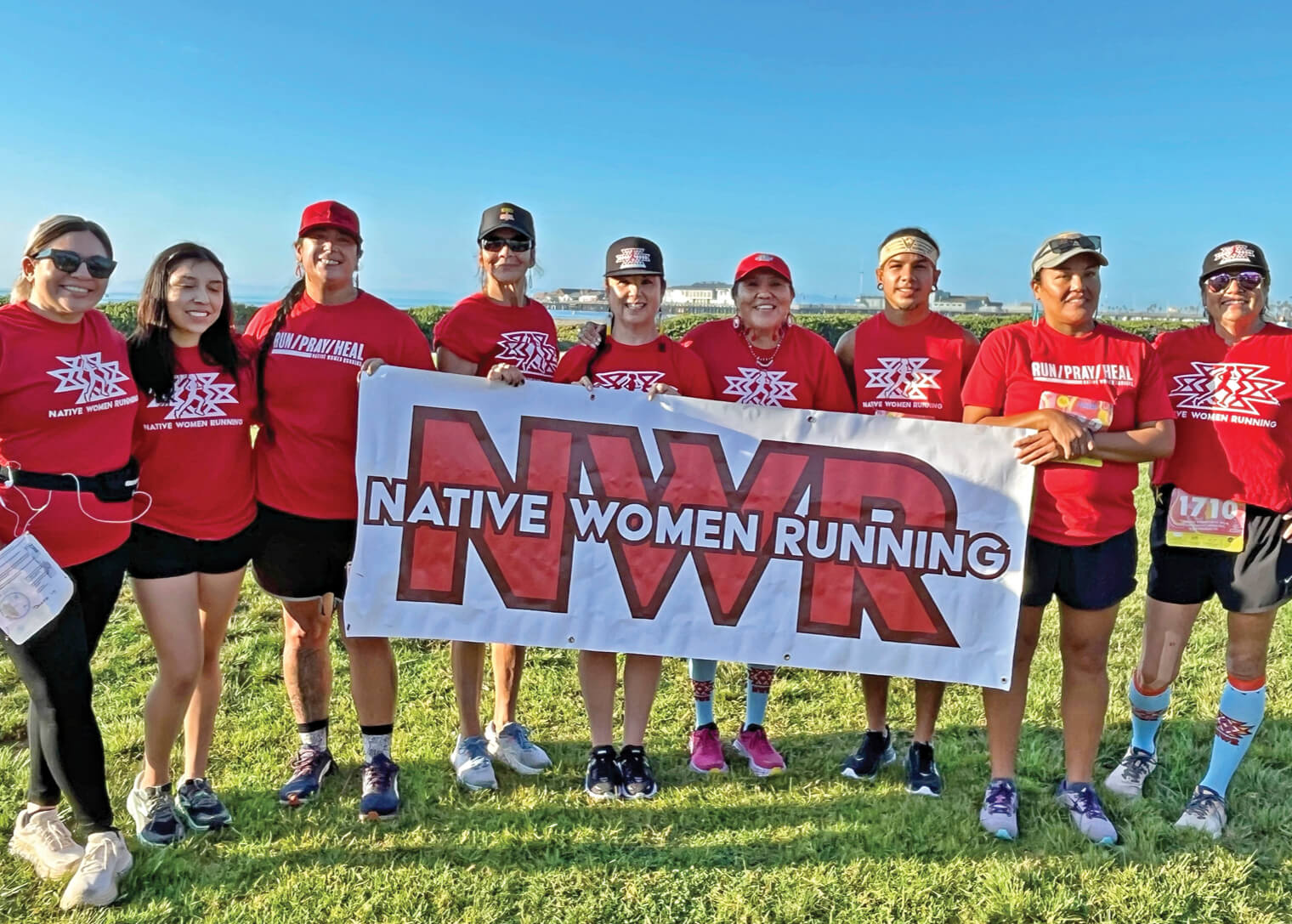 Photo of Verna Volker with fellow runners holding a banner that says Native Women Running