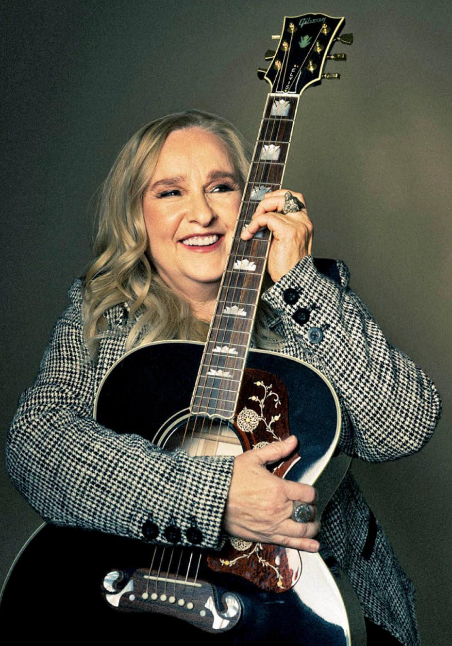 Photo of a smiling Melissa Etheridge holding a guitar