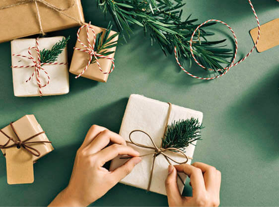 Photo of hands tying a gold ribbon on a small gift package