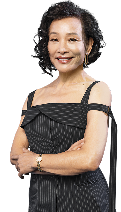 Portrait of Joan Chen standing with her hand crossed. She is wearing a pinstriped black jumpsuit, and she is wearing her hair down and wavy 