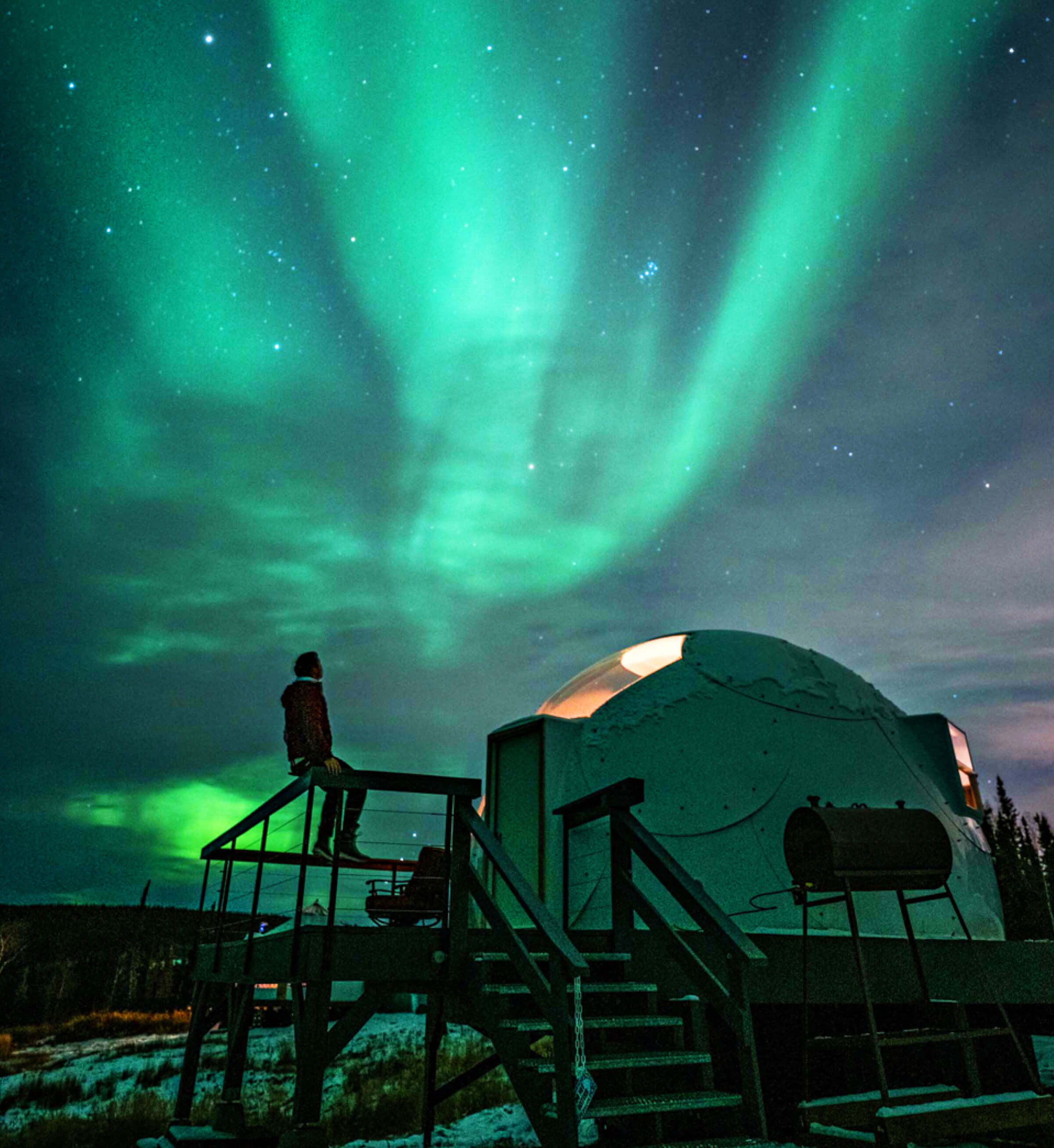 Photo of a camping dome with the northern lights visible above