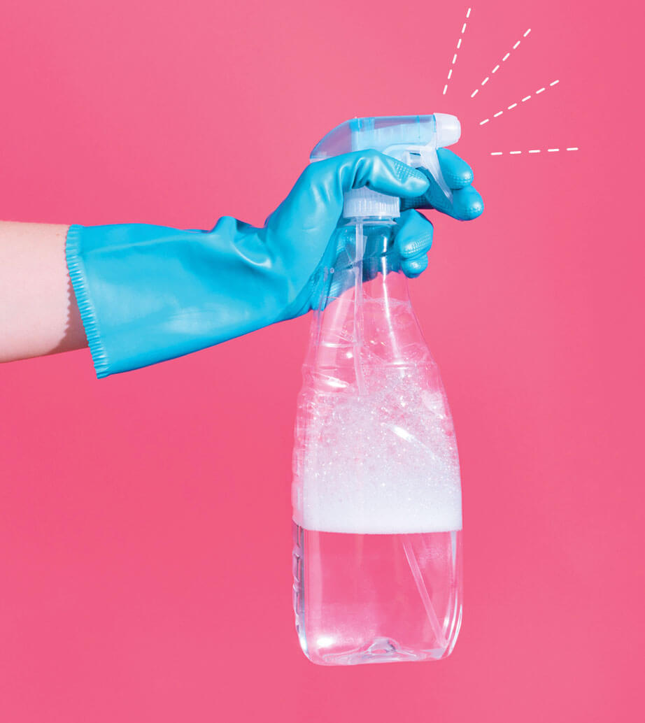 Photo of a hand wearing a blue cleaning glove, holding a cleaning spray bottle