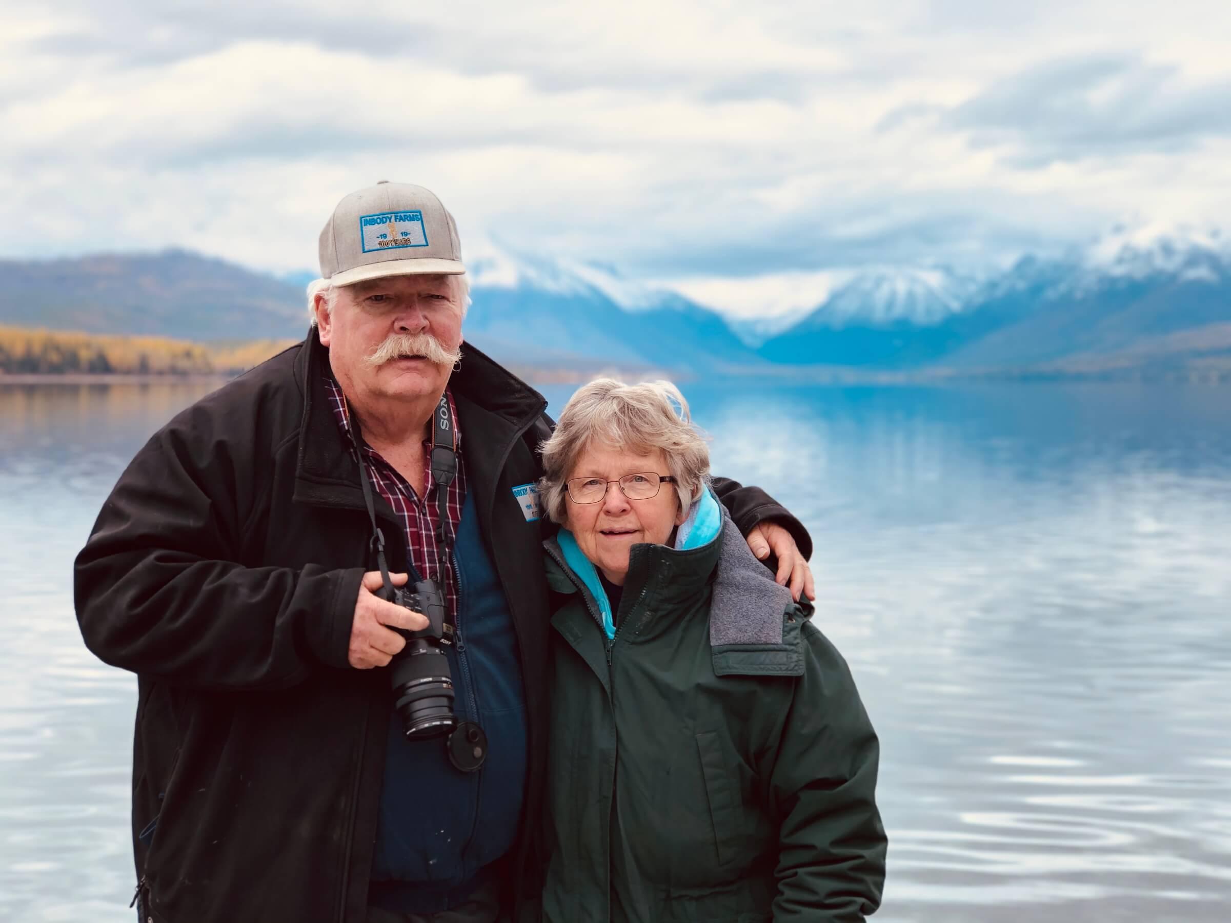 Image of Roy and Diane Inbody in front of a lake with snowcapped mountains behind them