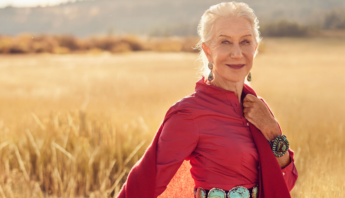 Photo of Helen Mirren in a red dress standing in a large open field