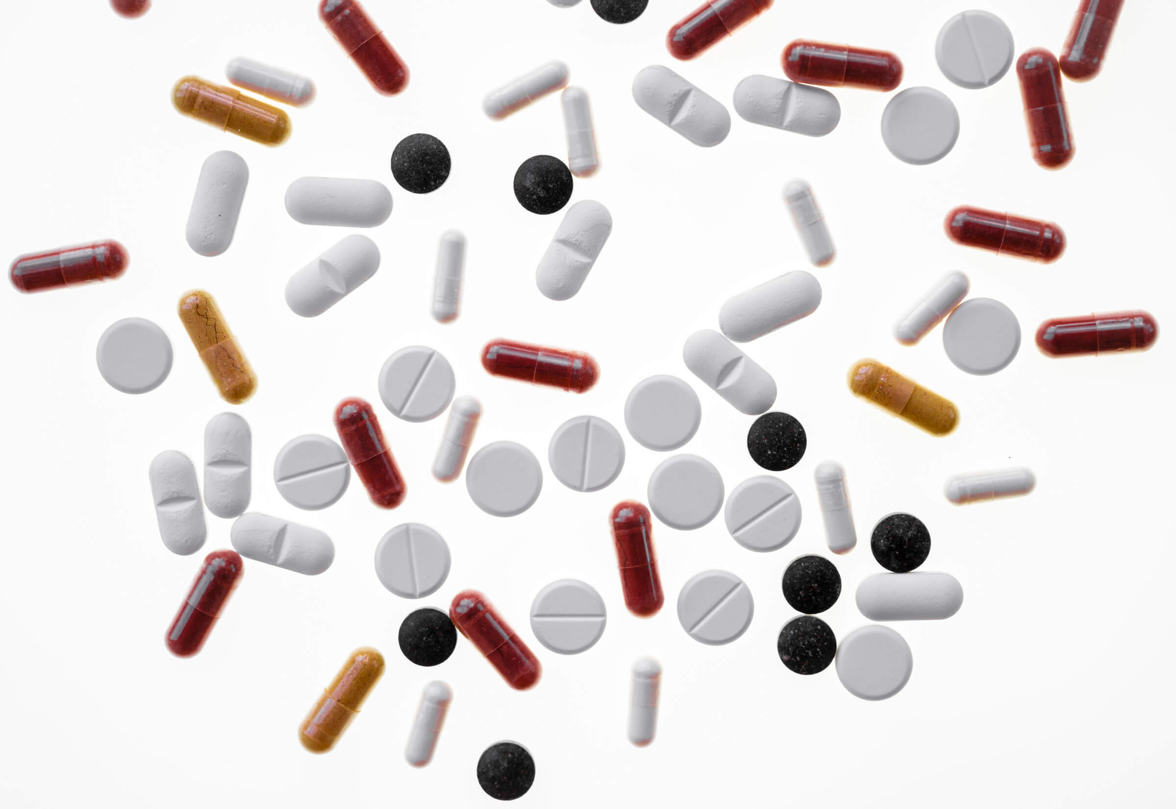 Photo of a bunch of various pills and capsules on a white background