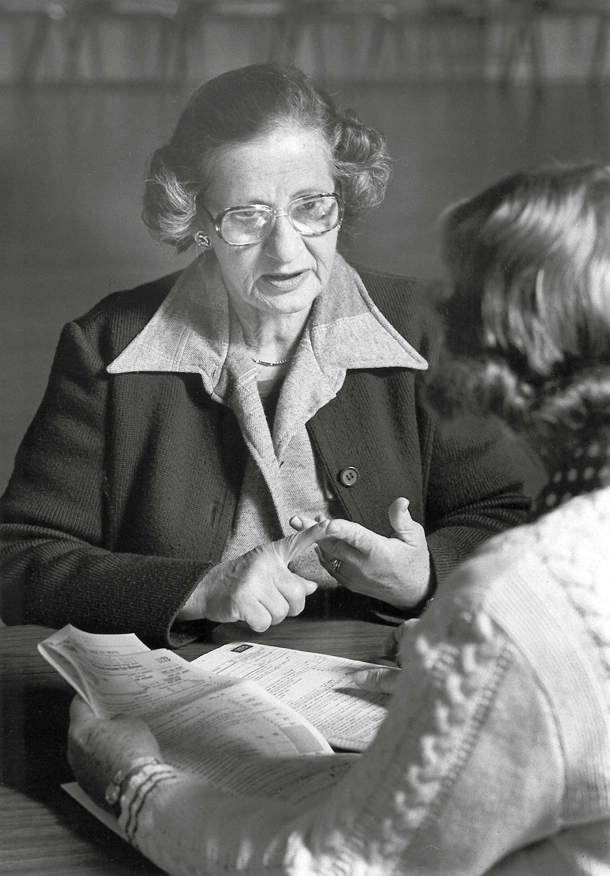 Vintage black and white photo of 2 woman having a tax-aide discussion