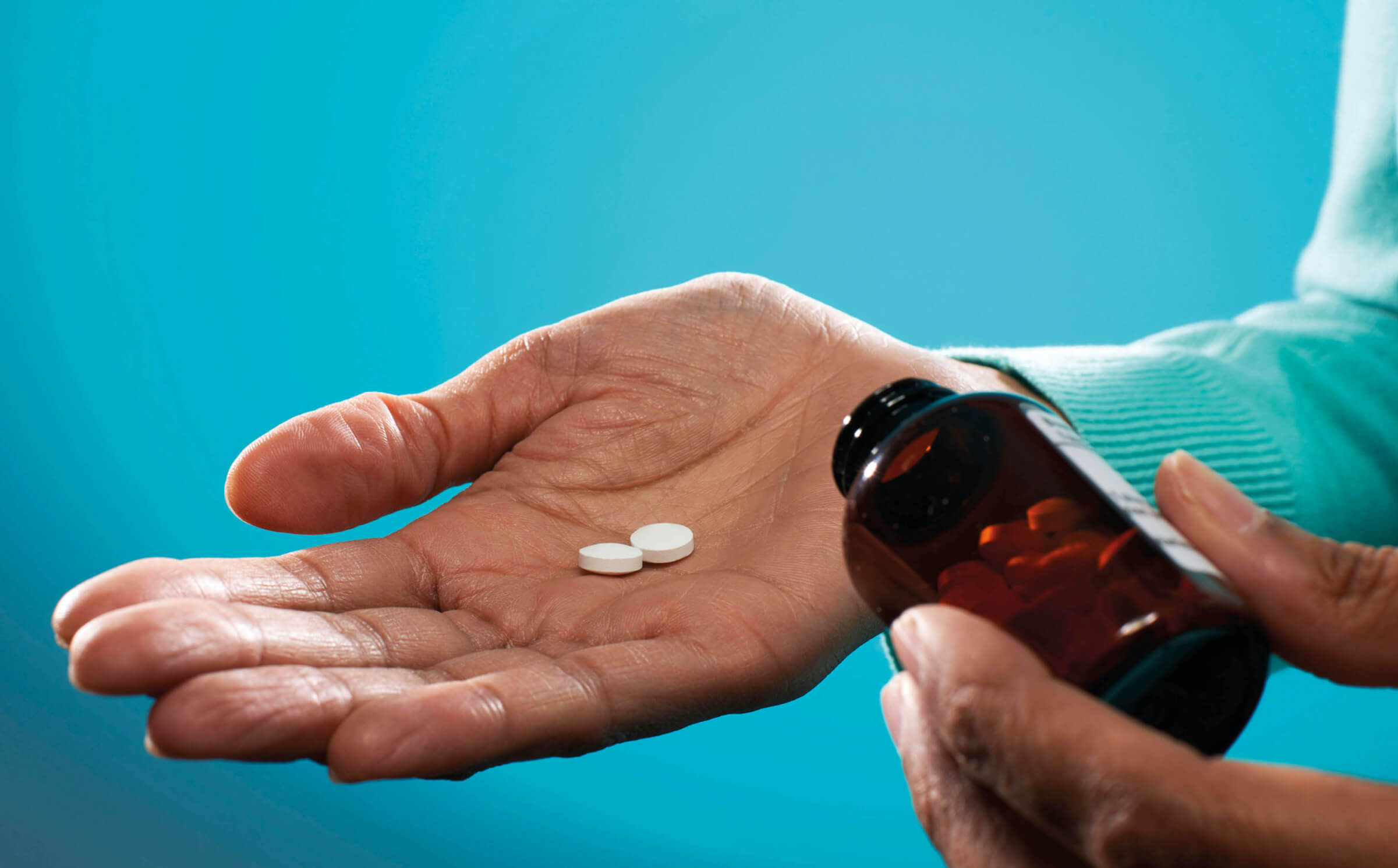 Photo of a hand holding two white pills