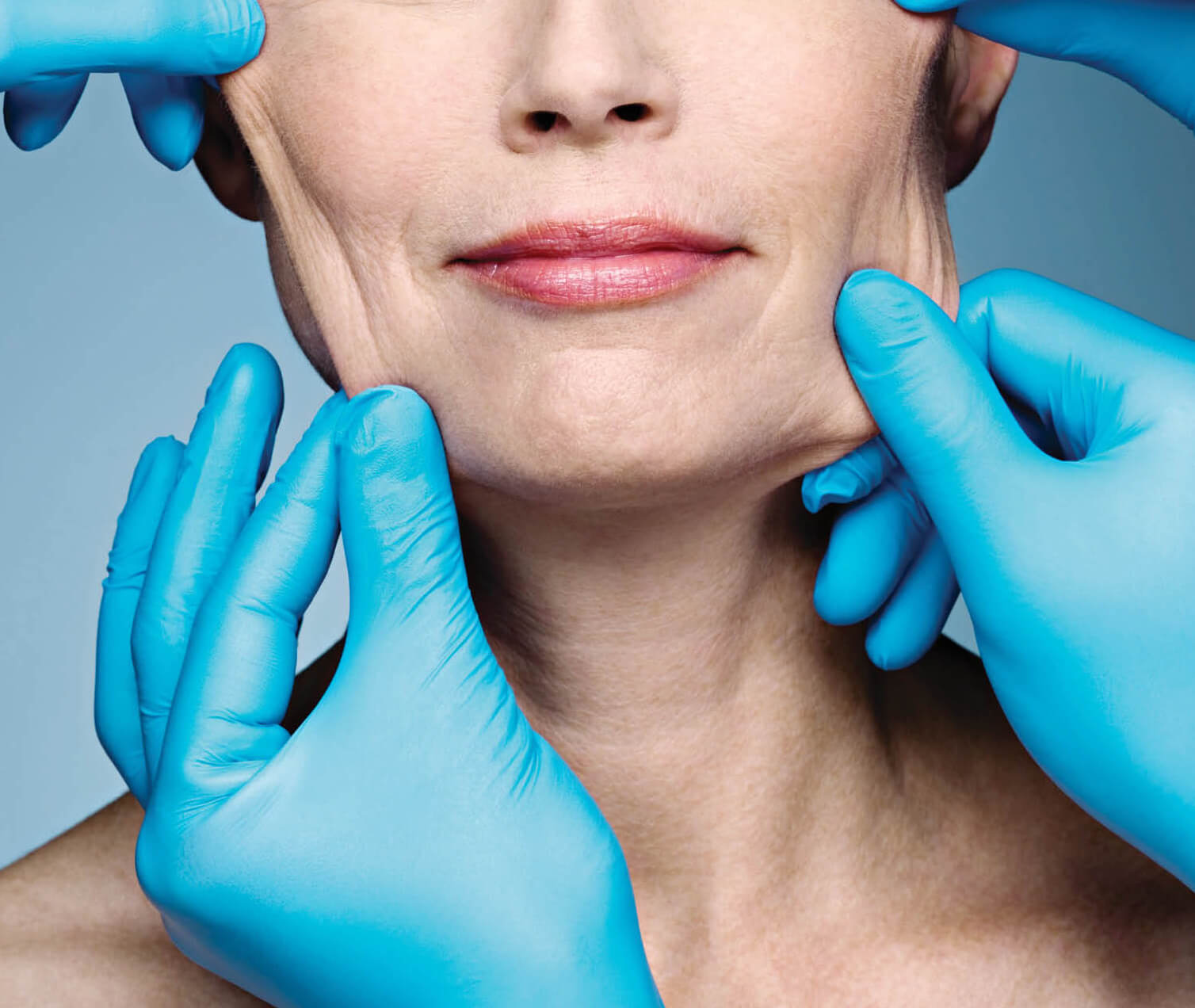 Photo of a woman's face being pulled at by gloved hands