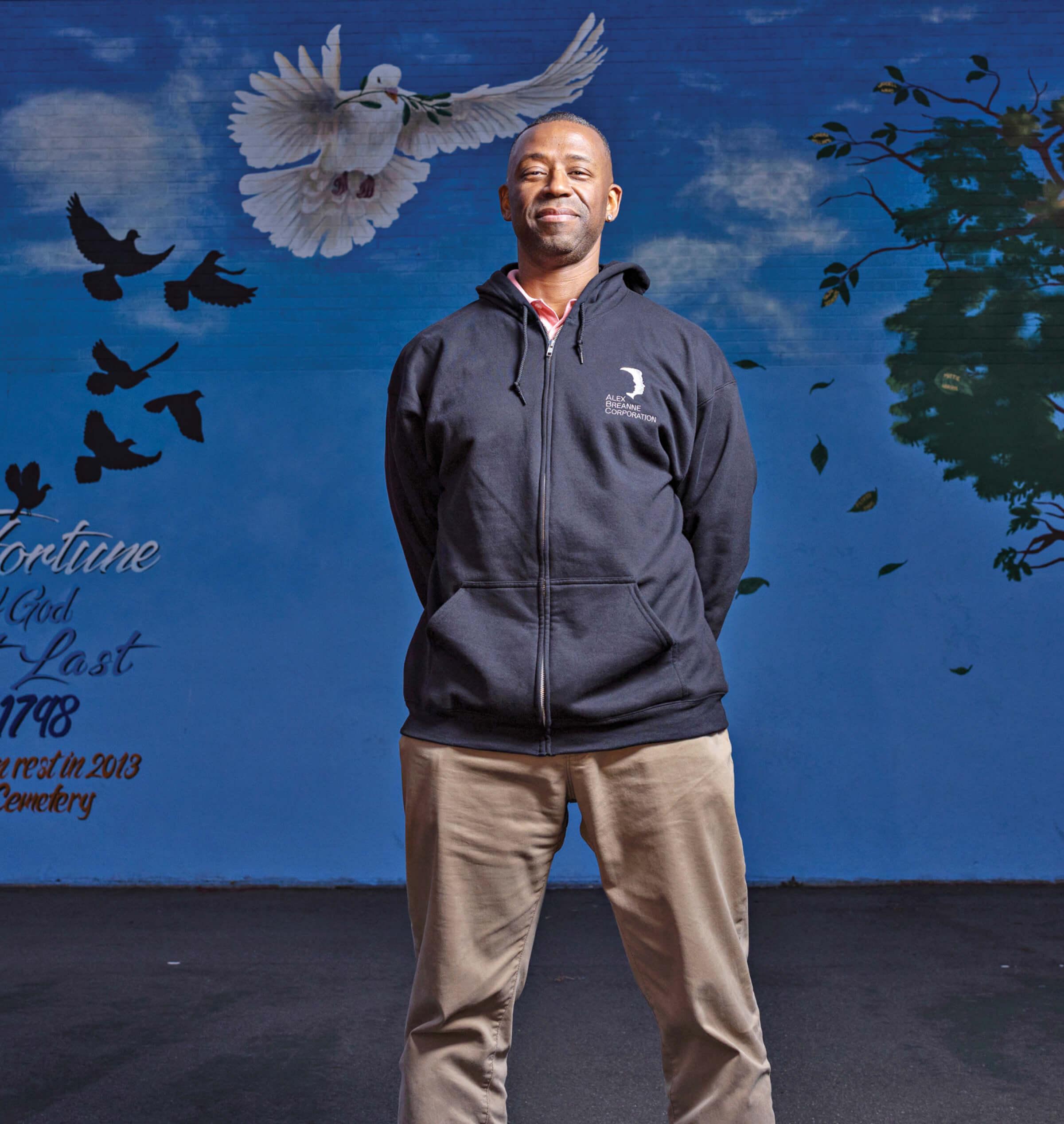 Portrait of John Mills in front of a dove mural