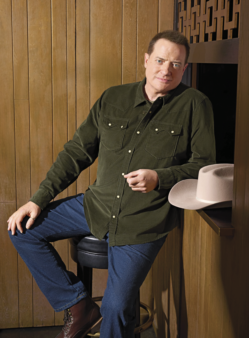 Image of him sitting on a bar stool in a olive-green button-down shirt&nbsp;