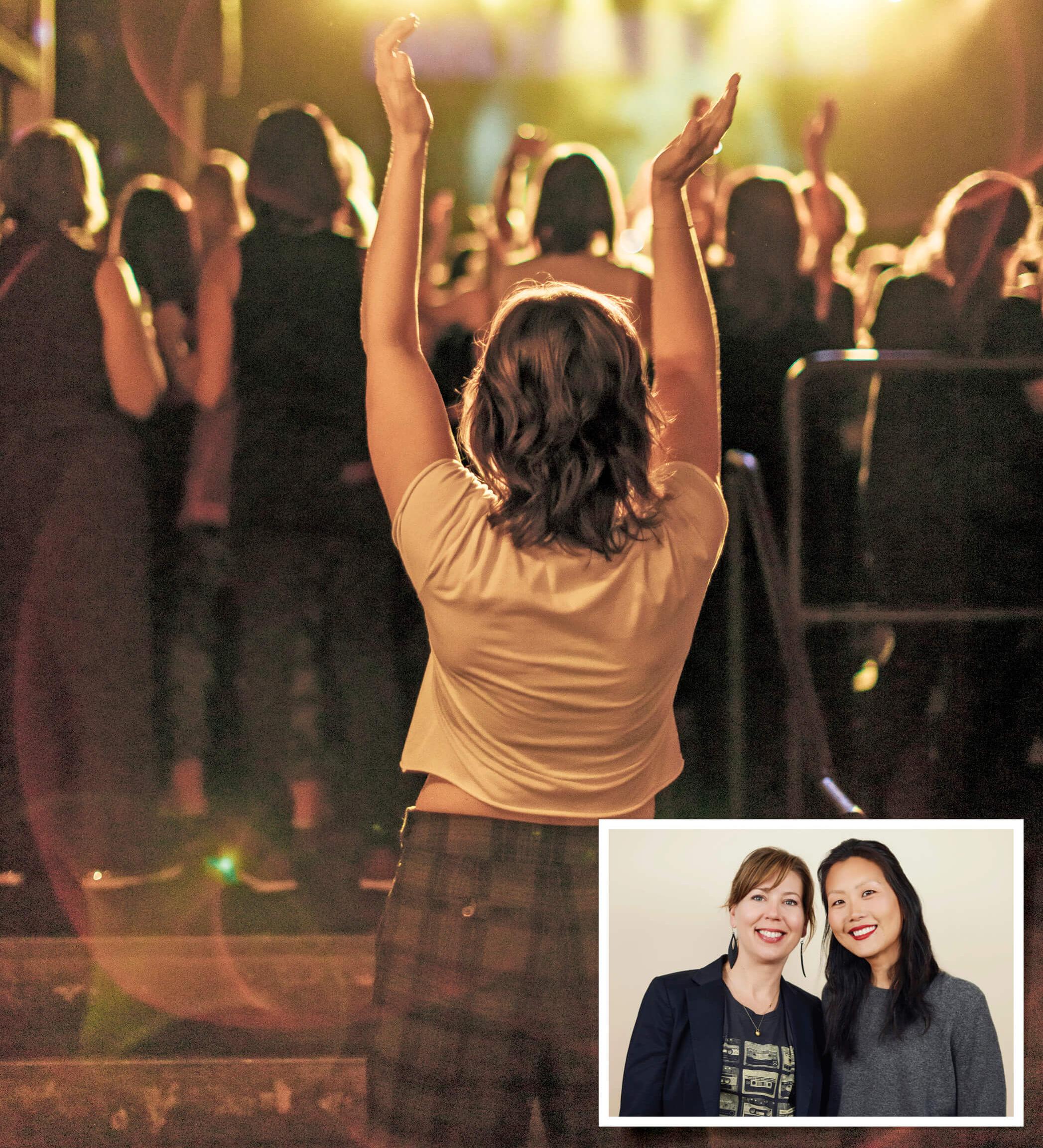 A woman standing in a crowd with her hands raised and clapping. Two woman standing next to each other and smiling&nbsp;
