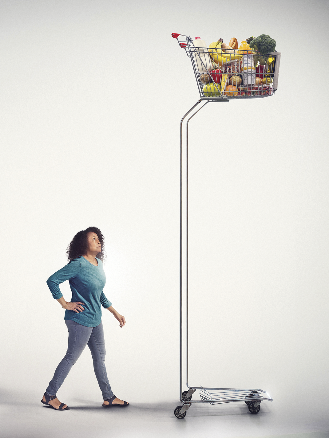 Woman standing looking at a very tall grocery cart