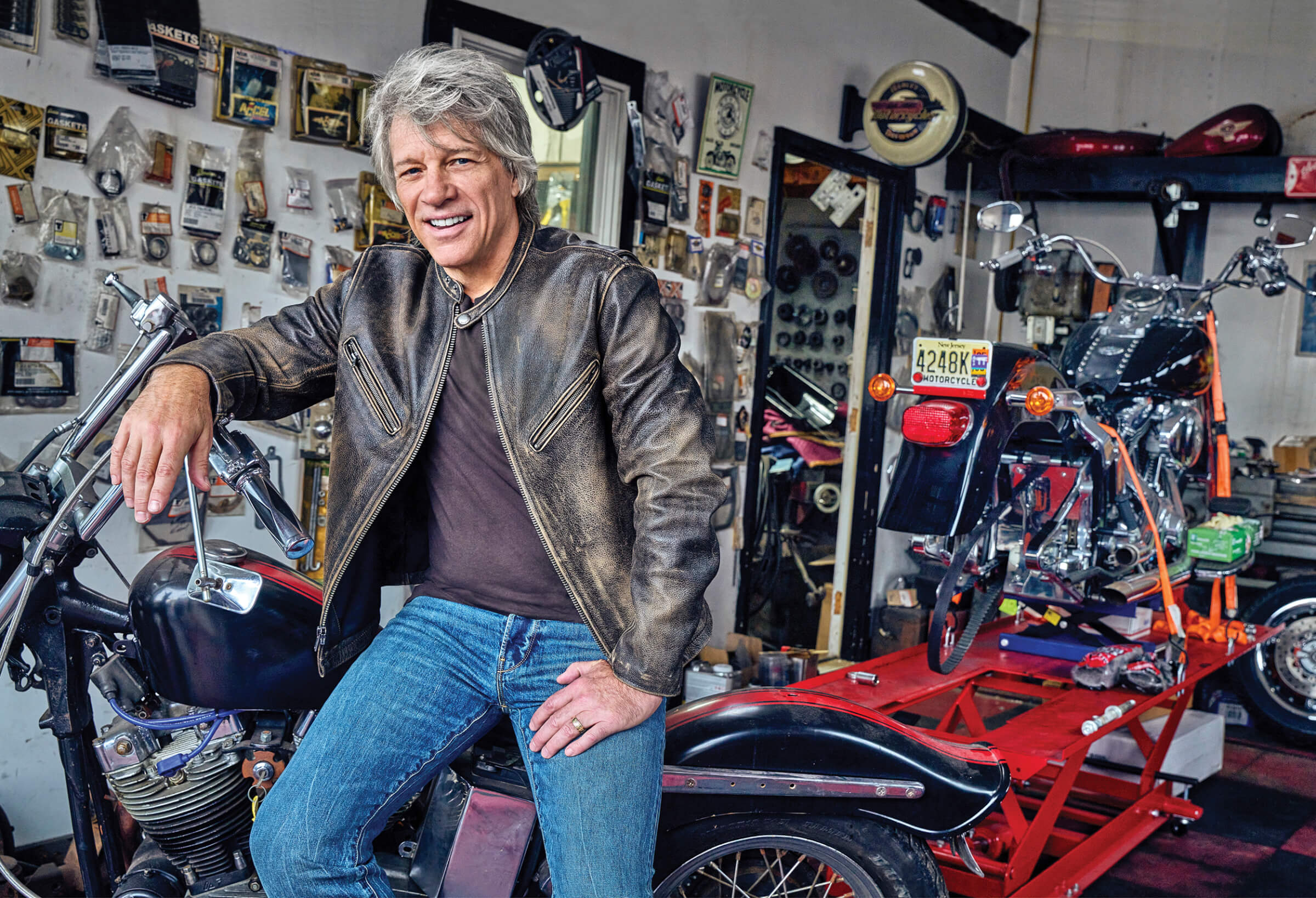 Photo of Bon Jovi sitting on a motorcycle in a garage workshop