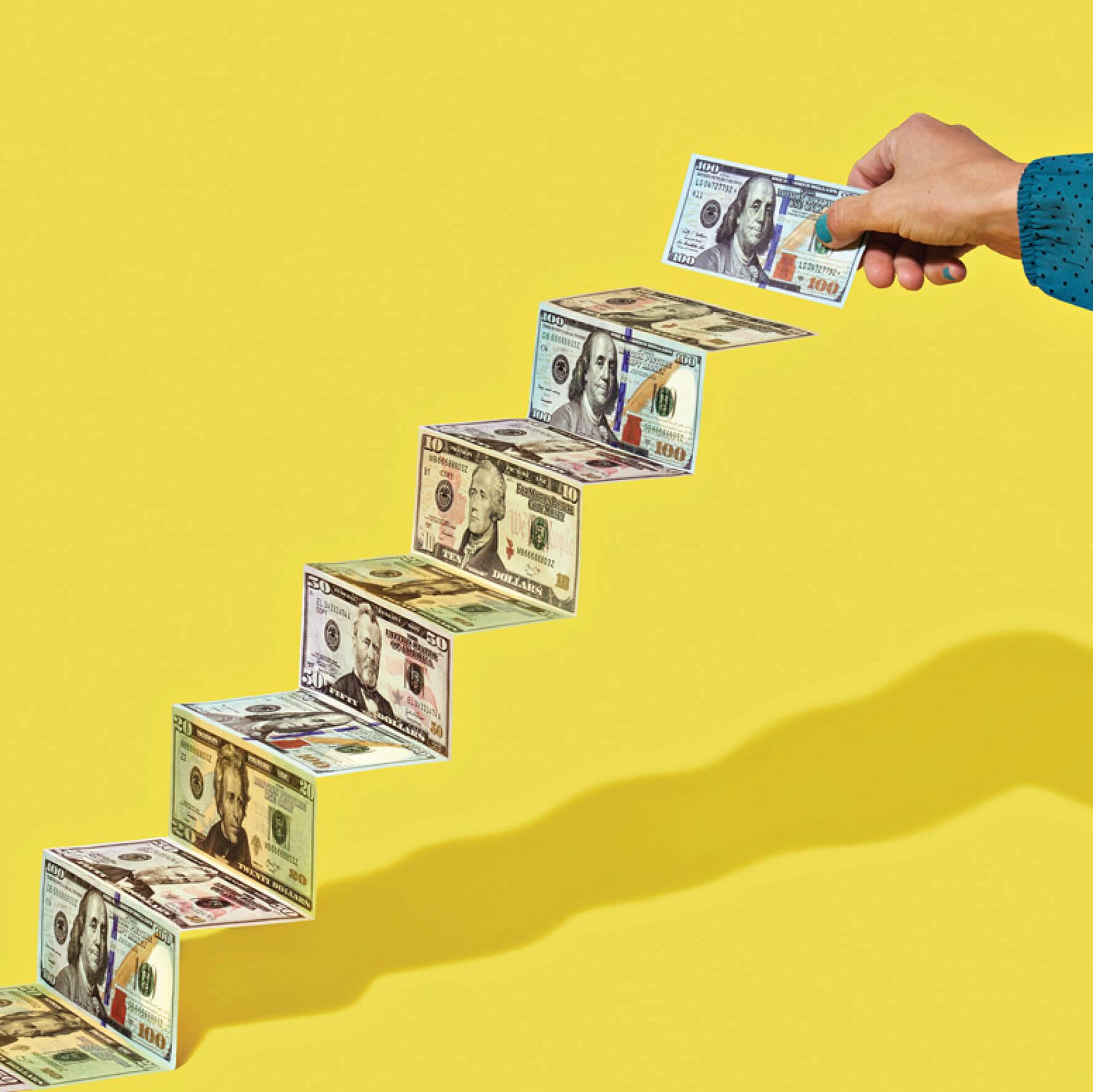 Photo illustration of a hand stacking dollar bills to make an ascending staircase