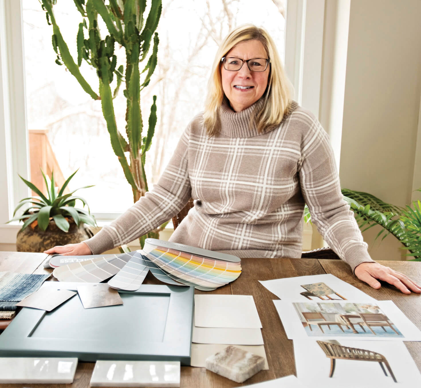 Photo of Janice Young sitting at desk covered with interior design plans and samples