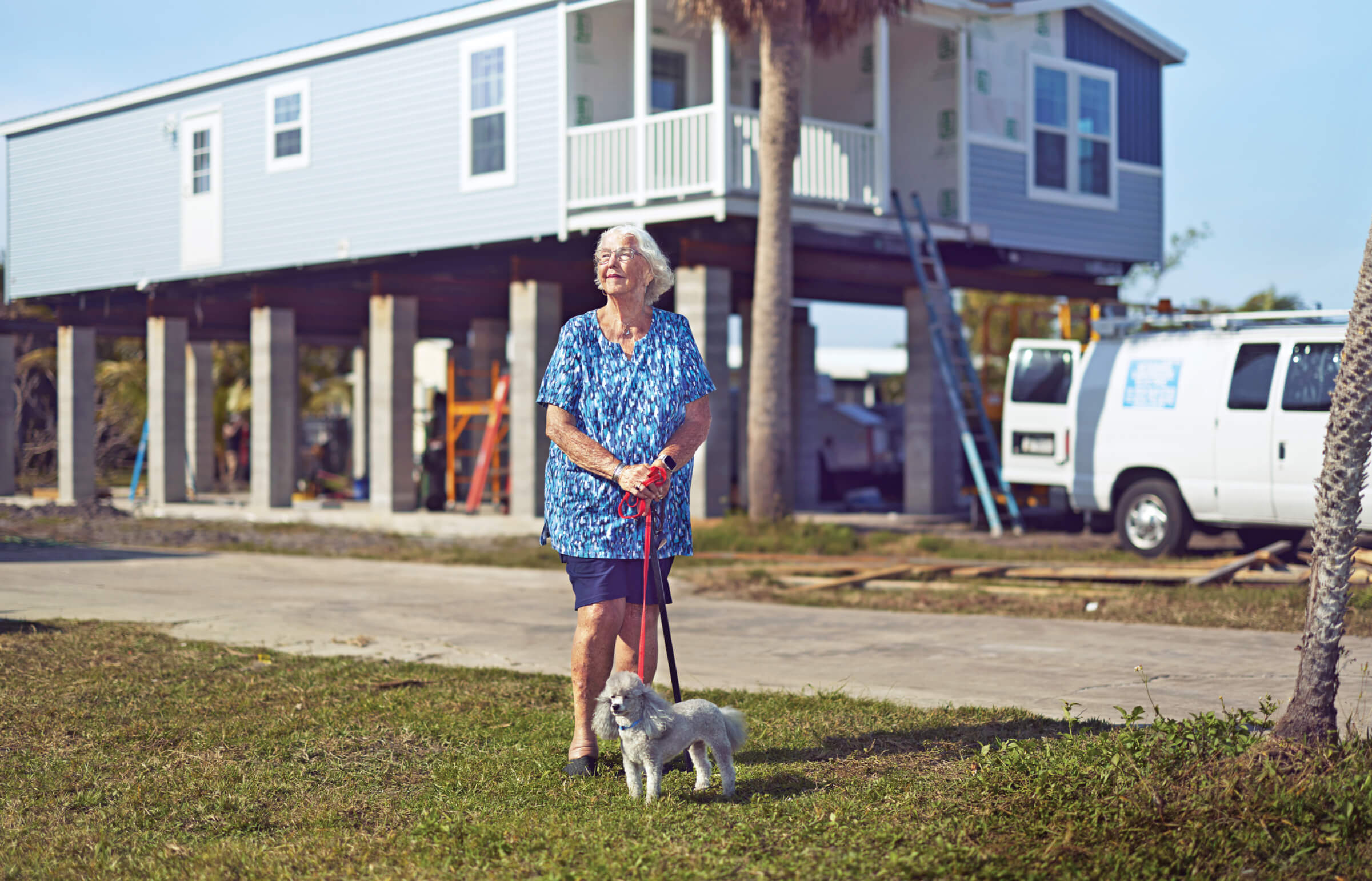 Photo of Martha Shaw and her dog in front of her new elevated mobile home