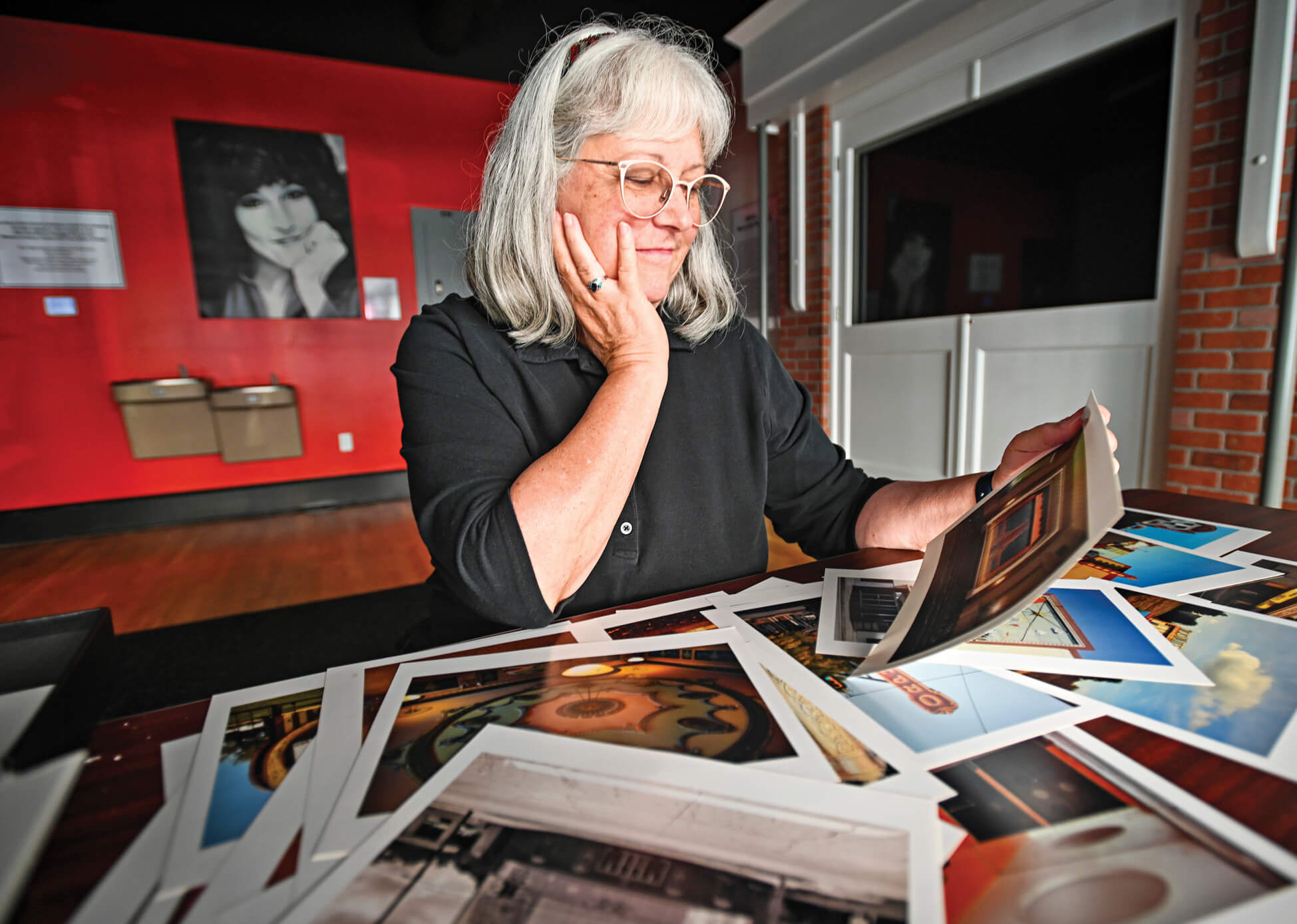 Photo of Benita VanWinkle looking at prints of her own photography