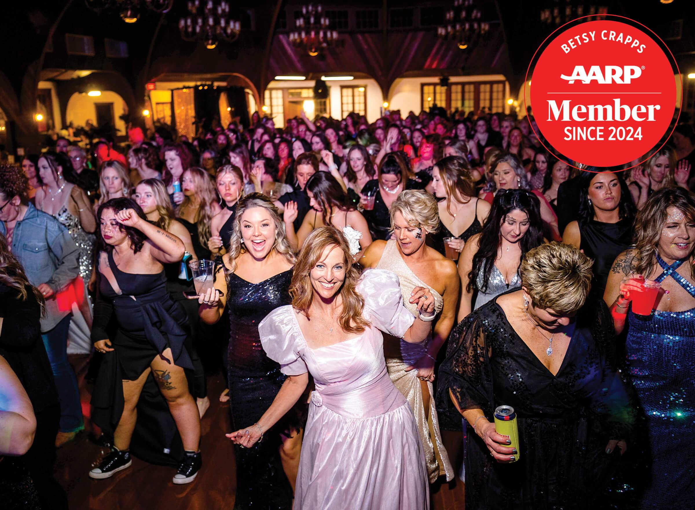 Photo of Betsy Crapps in a pink dress at the front of a dancing crowd
