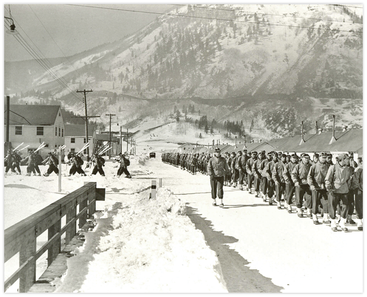 Older black and white photograph of the American troops standing in the snow between the mountains 