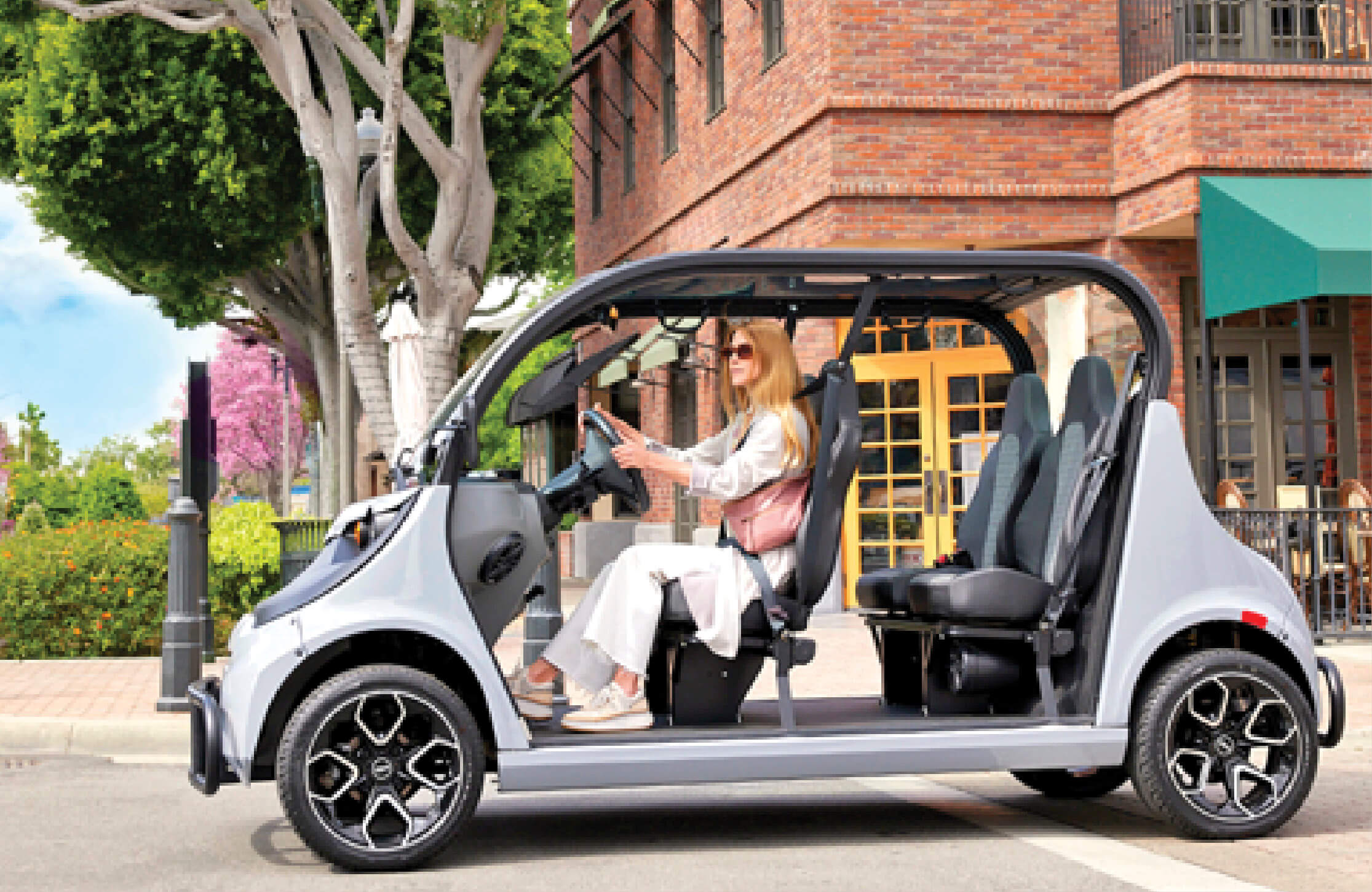 Photograph of a woman driving a small battery powered car on the street.