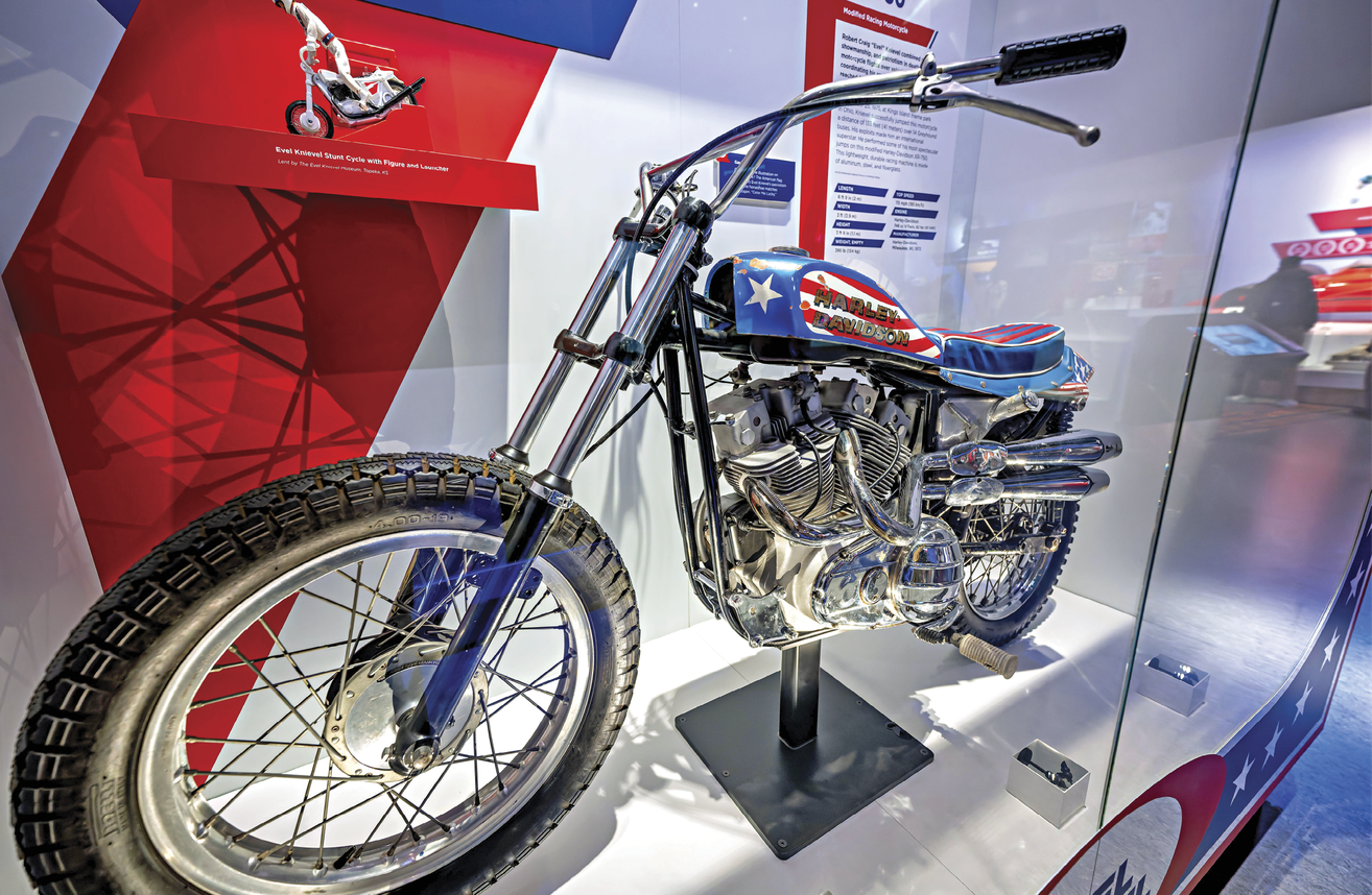 Photograph of Evel Knievel’s bike on display, behind a glass case 