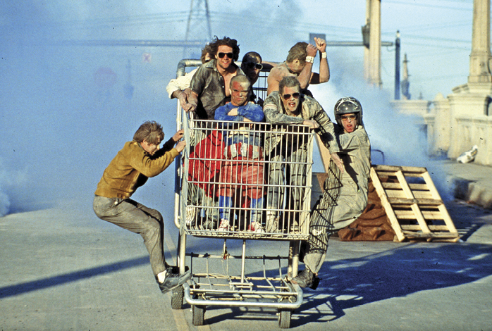 Several people sitting in a shopping cart on the road 