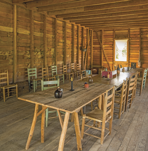 Photograph of the inside of the reconstructed town, showcasing tables and chairs in a log cabin