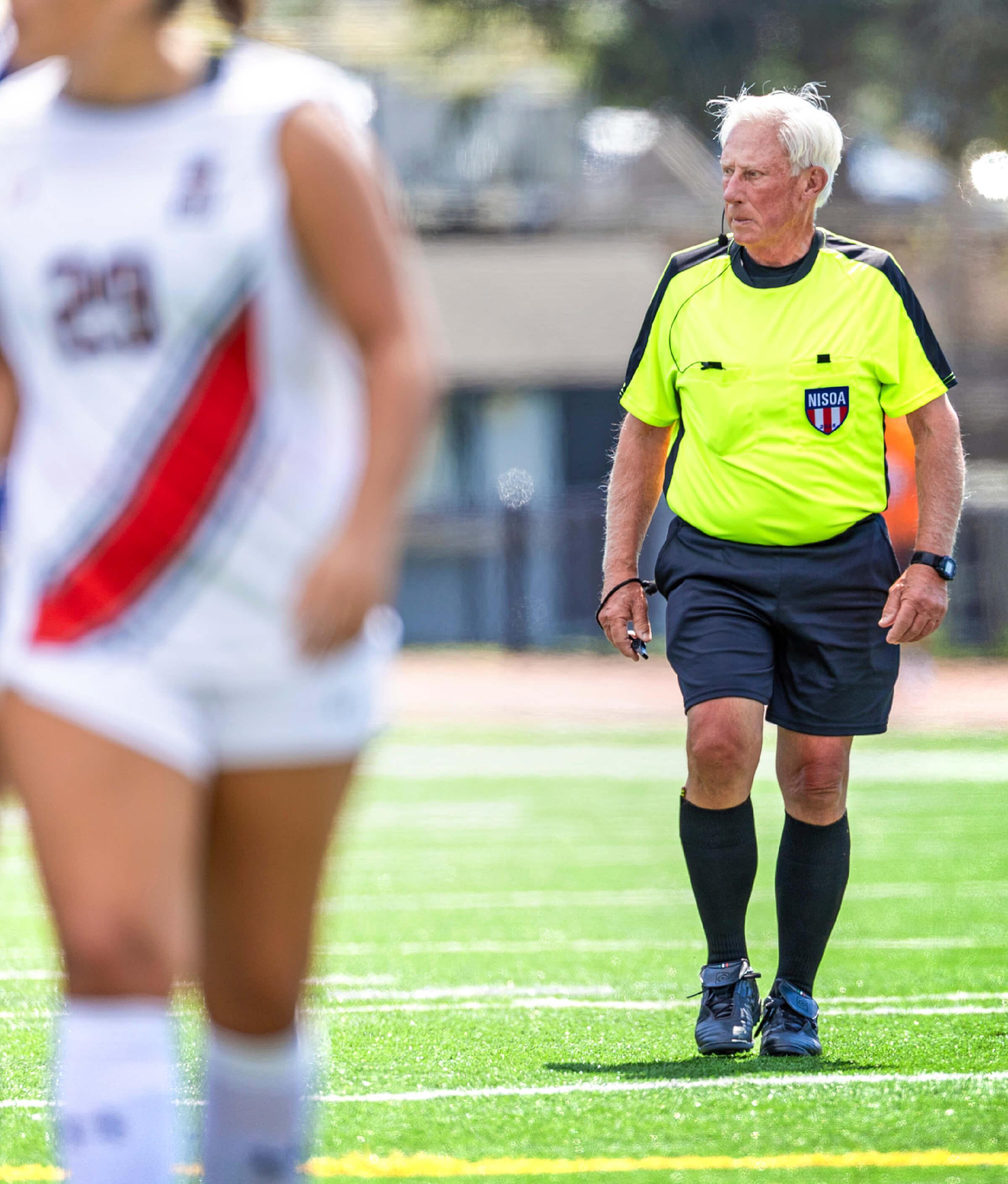 Image of Neal Kennedy in a soccer referee attire walking on the soccer field 