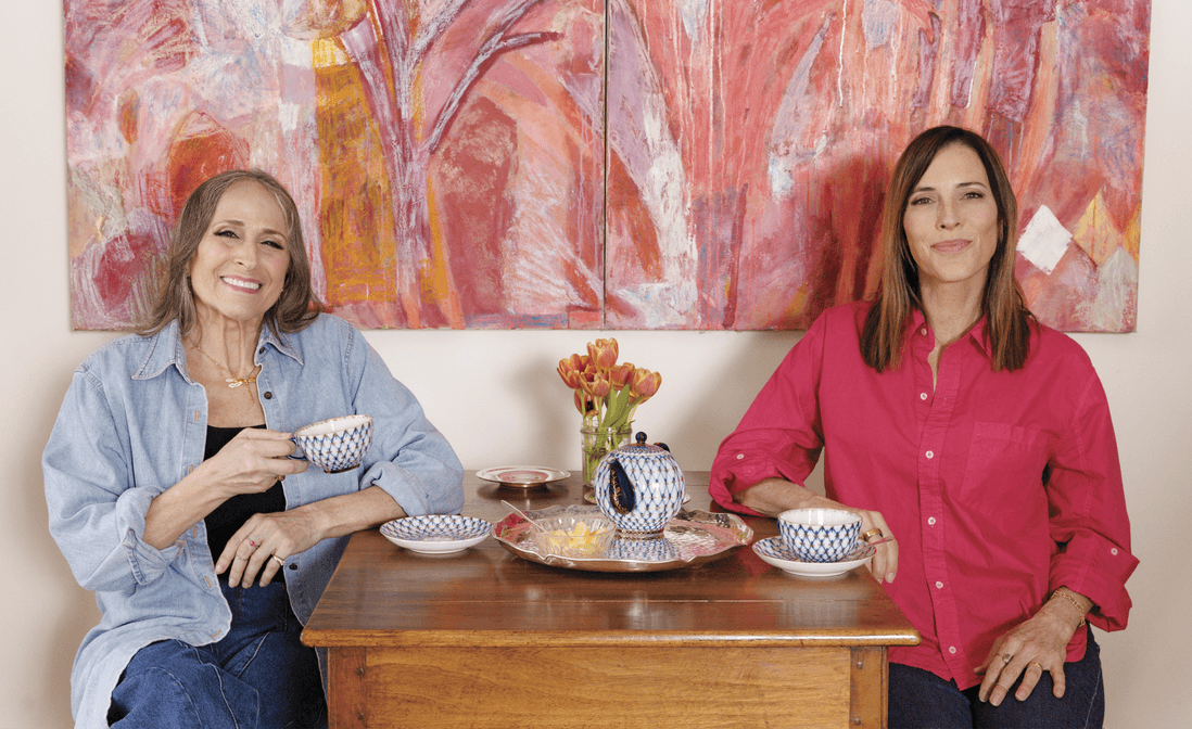 Photograph of Janne Gefland and Cecilia Peck sitting at a table and drinking tea. They are looking at the camera and smiling 