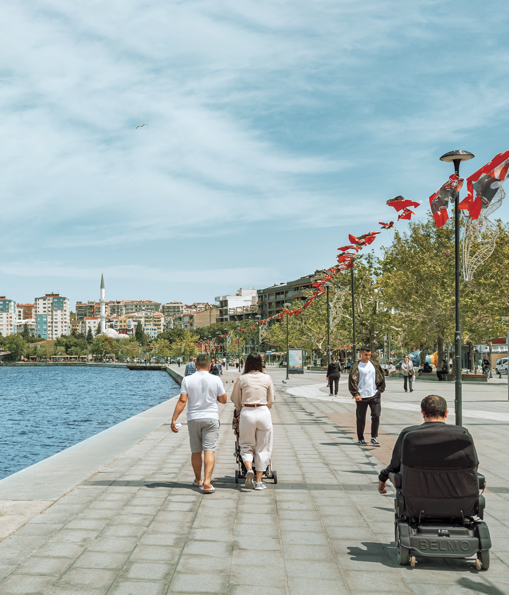 Photograph of a person on a wheelchair on a street by water 