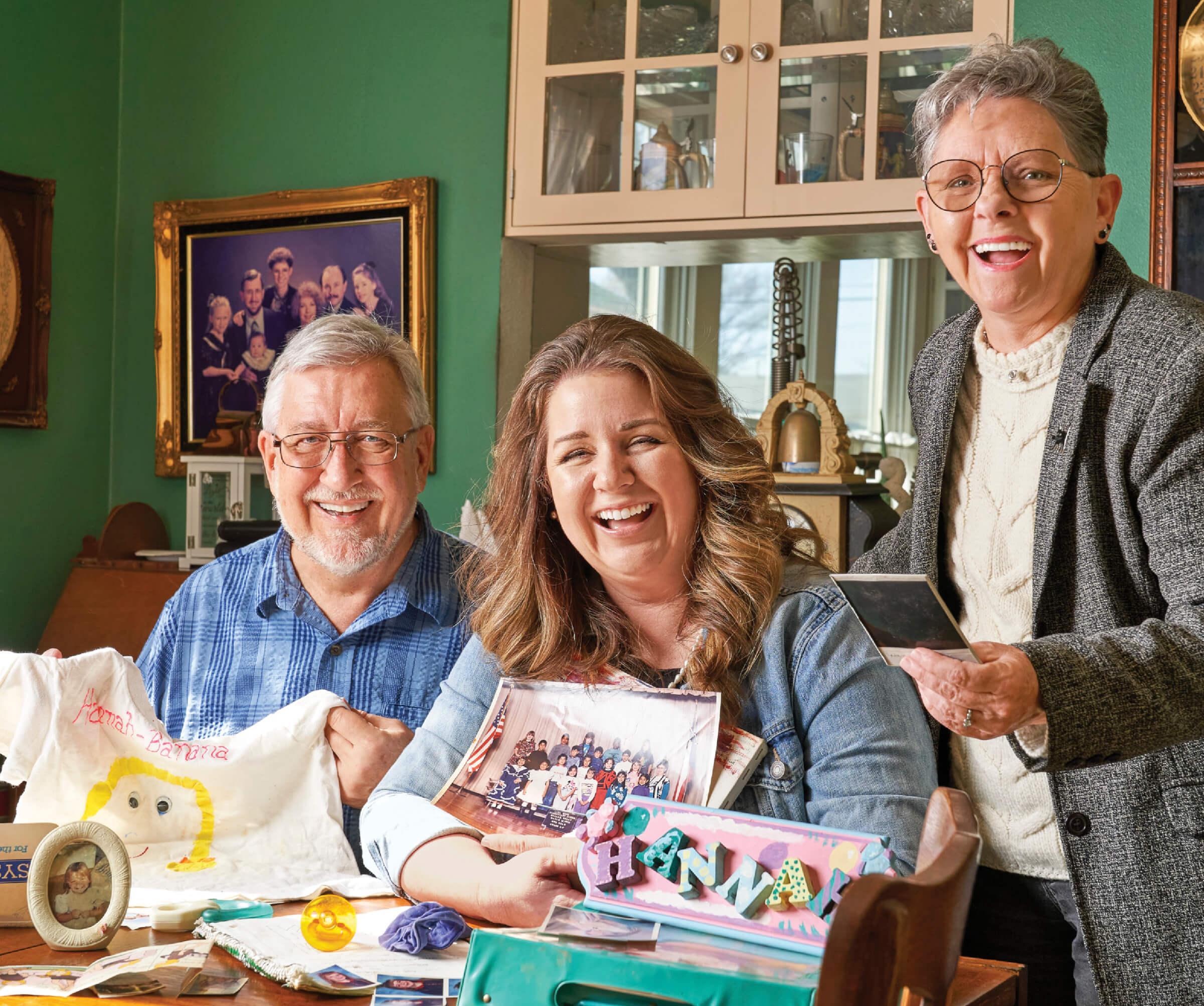 Photograph of the Ericksons with their neighbor Hannah Mitchell, sitting at a table with various gifts around them 