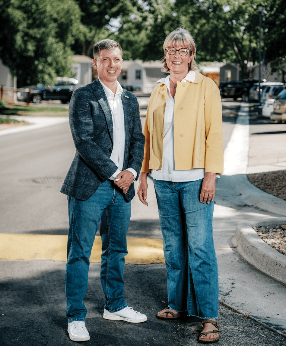 Photograph of Littleton Mayor Kyle Schlachter and County. Commissioner Carrie Warren-Gully standing next to each other in the streets and smiling at the camera