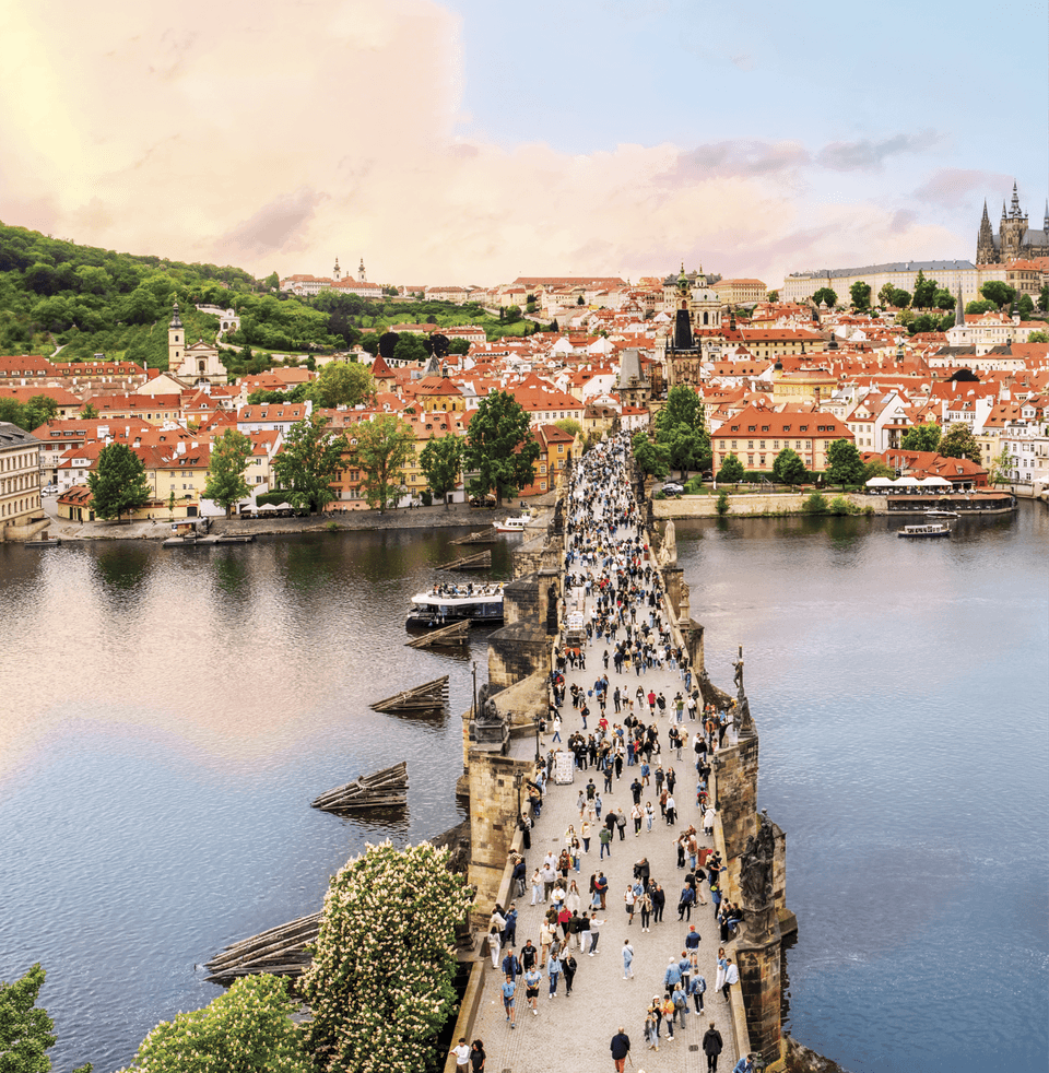 Top view of a photograph of a bridge across a river with a bunch of people walking down the bridge 