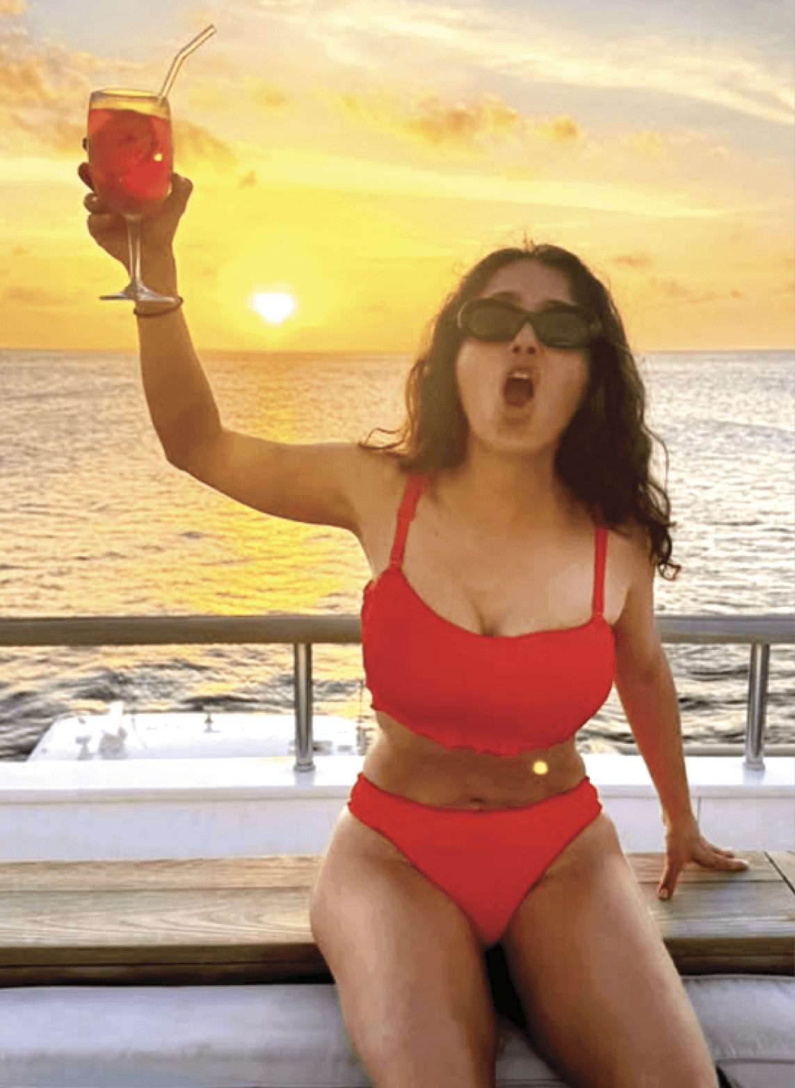 Photograph of Salma Hayek wearing a red bikini and holding up a cocktail 