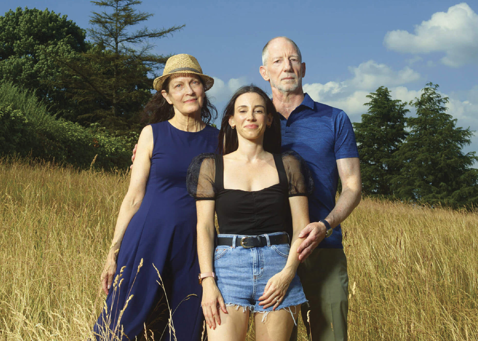 Photo of Suzanne and John Capouya standing in a field with Alexandra between them