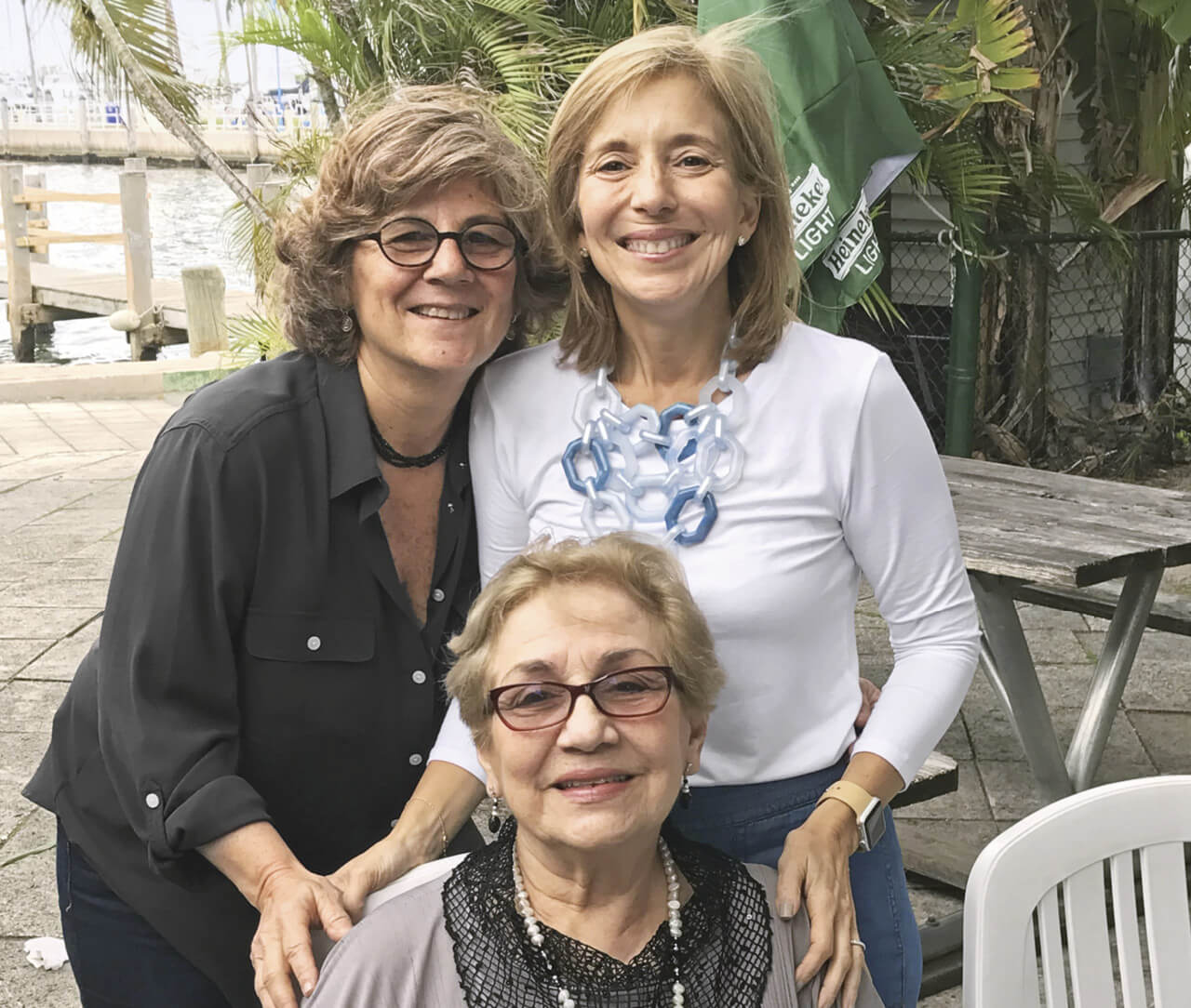 Photo of Debbie and Annette Franqui standing behind their seated mother Ginny Catinchi