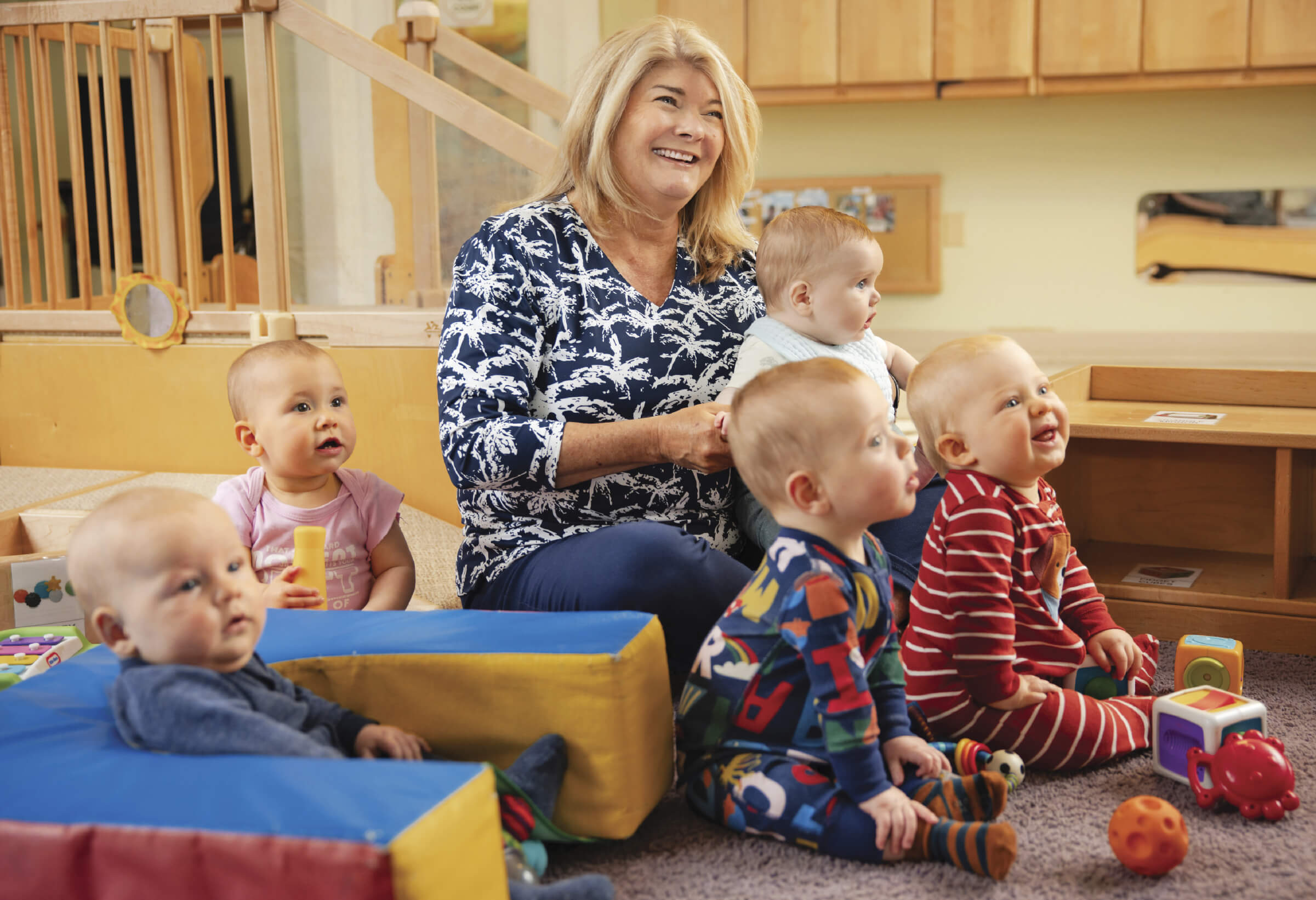 Photo of Jaimie Seaton sitting amongst the infants she minds at day care