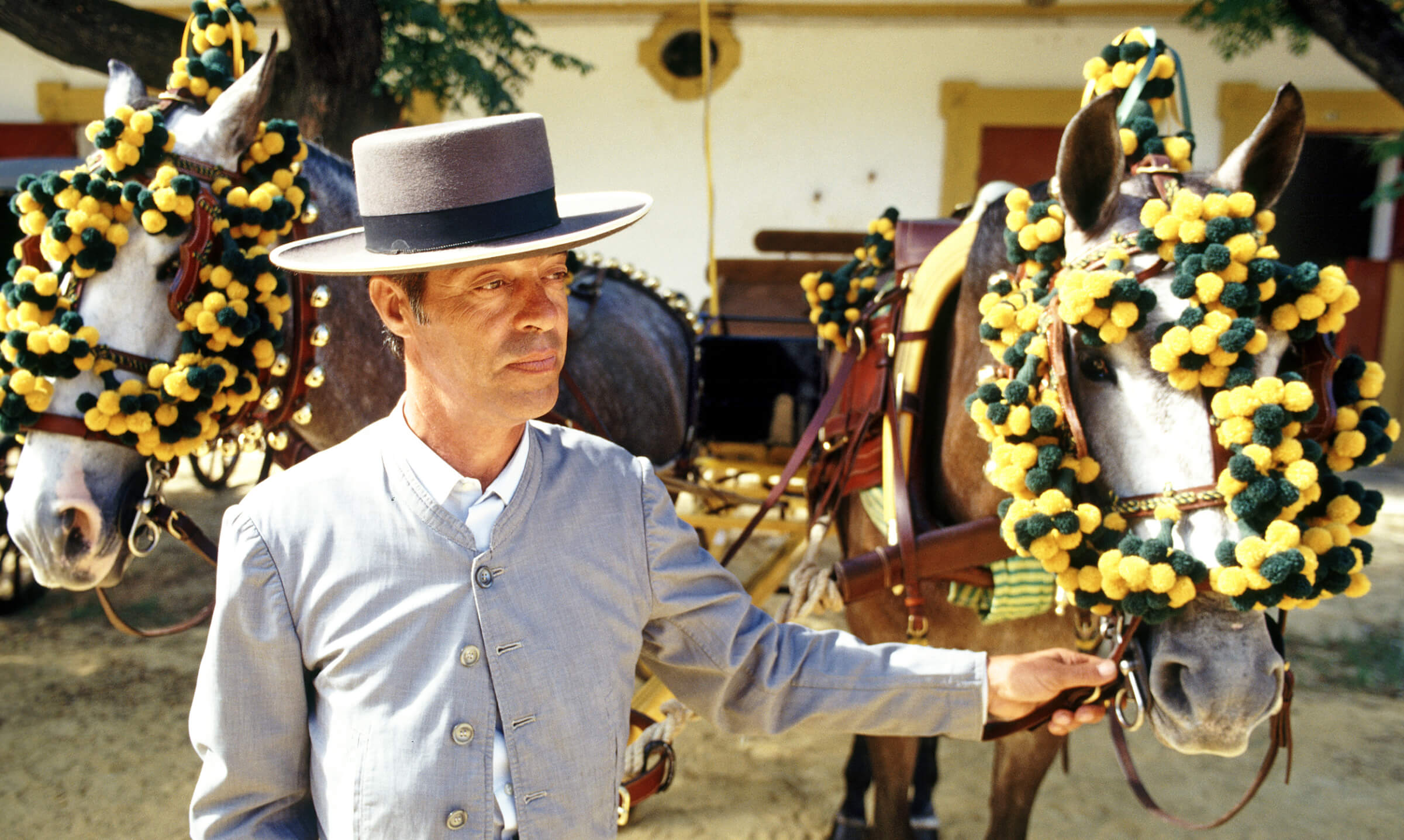 Photo of a traditionally-dressed man with 2 fancily-adorned donkeys in Jerez de la Frontera, Spain