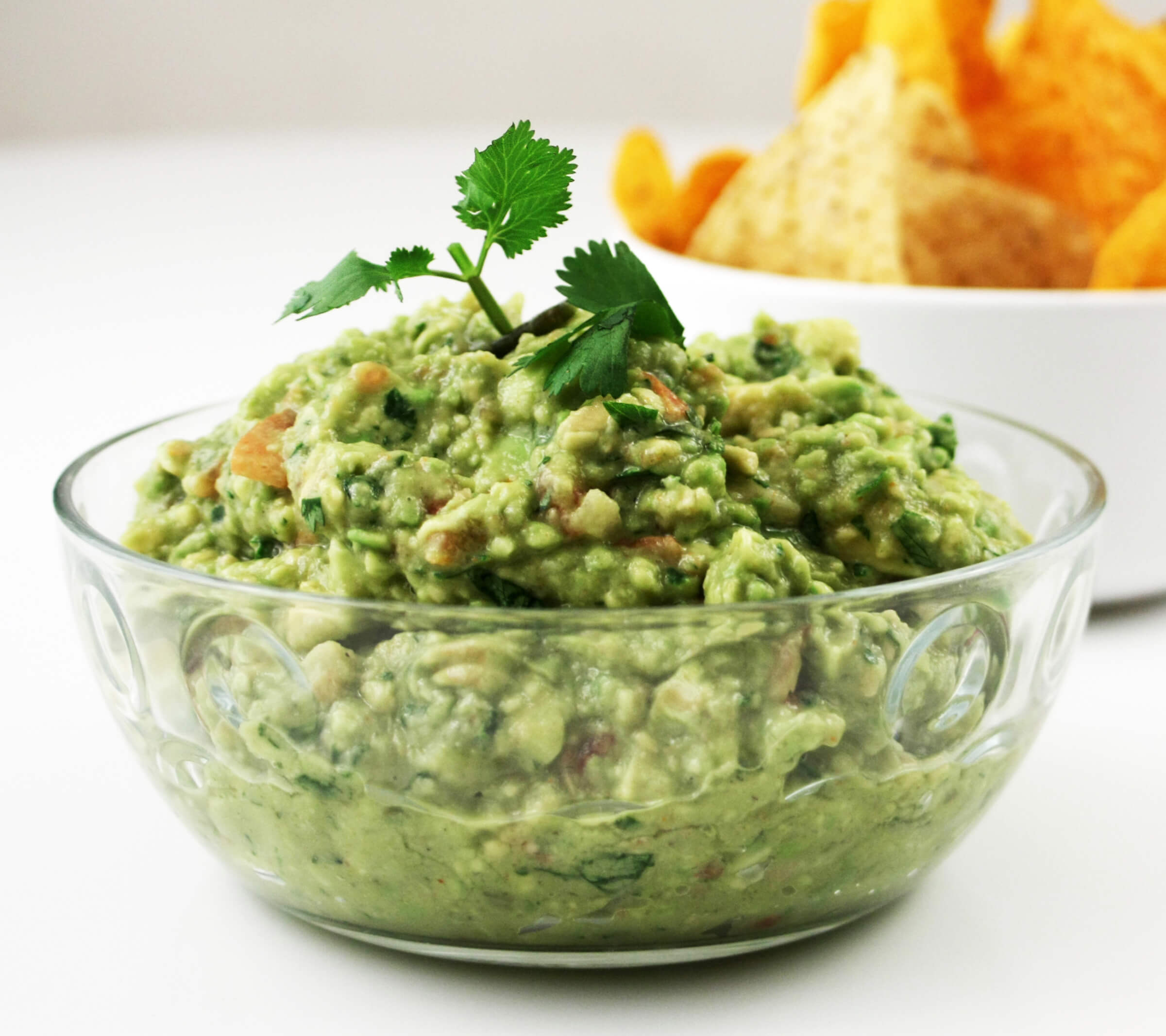 Photo of a bowl of guacamole topped with a sprig of cilantro