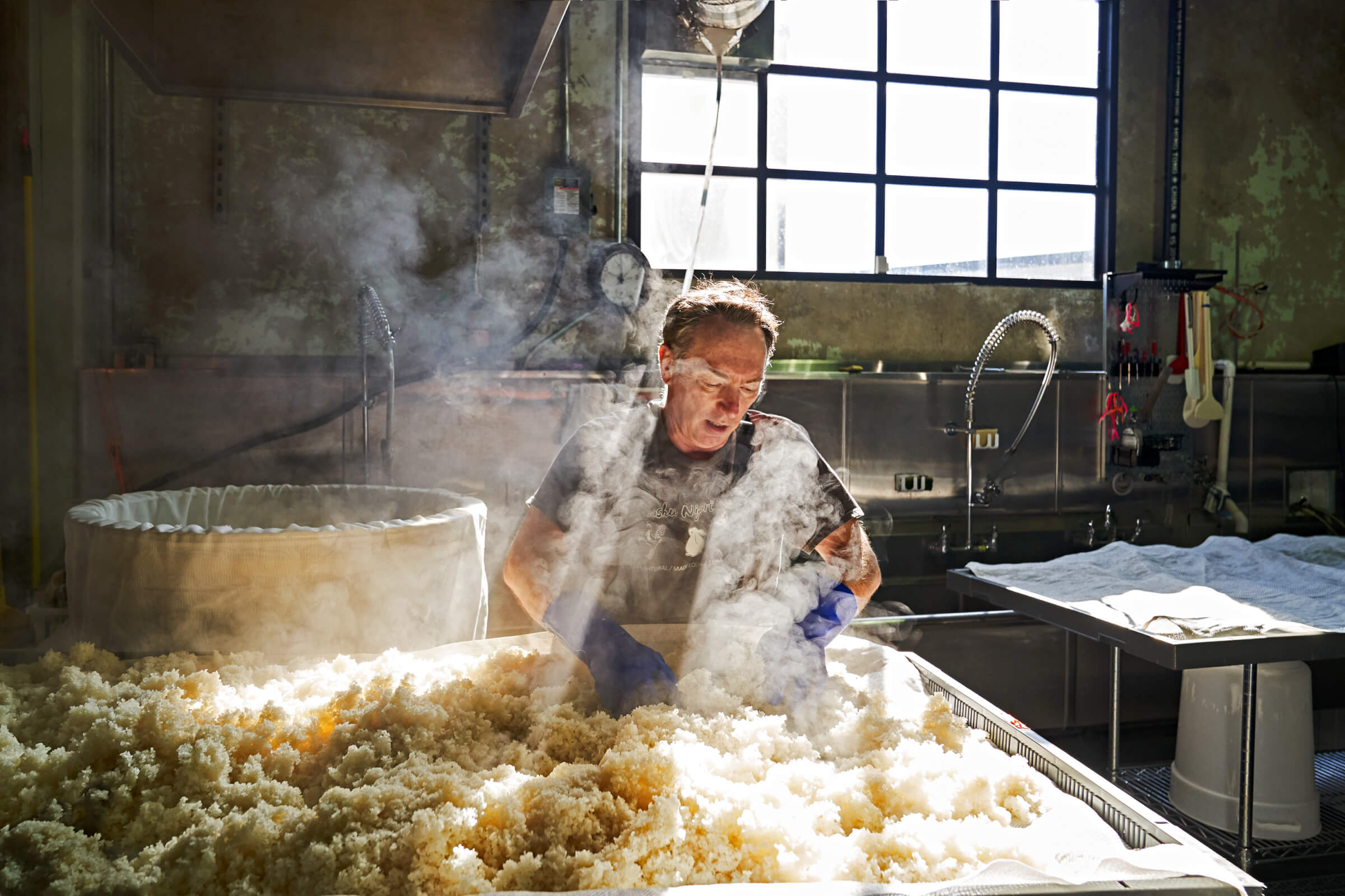 Photo of Jake Myrick spreading steamed rice onto racks for cooling