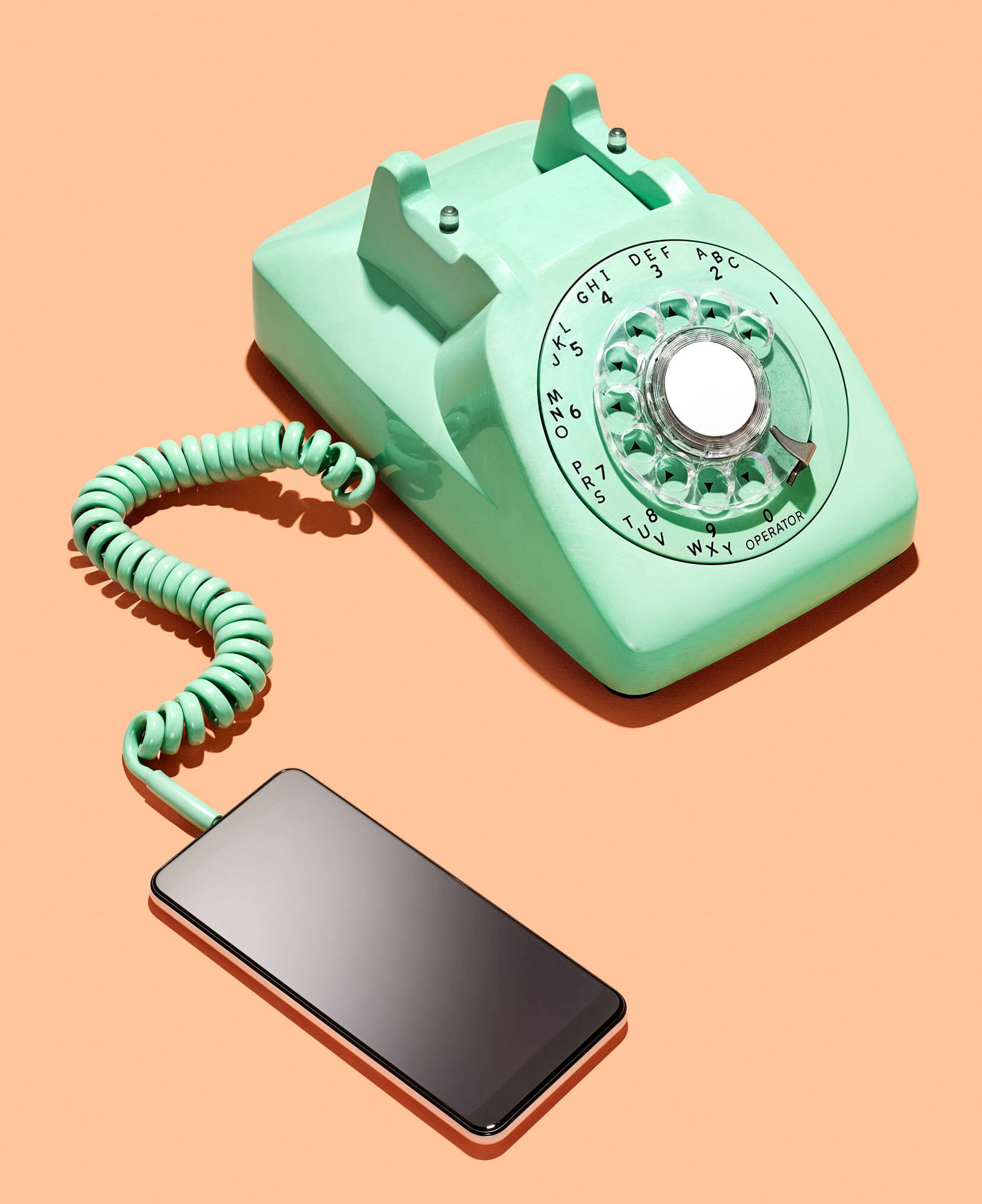 Photo of a landline telephone connected to a smart phone via a curly cord