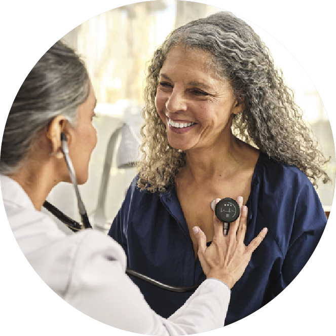 An older woman with curly grey hair being checked by a female doctor