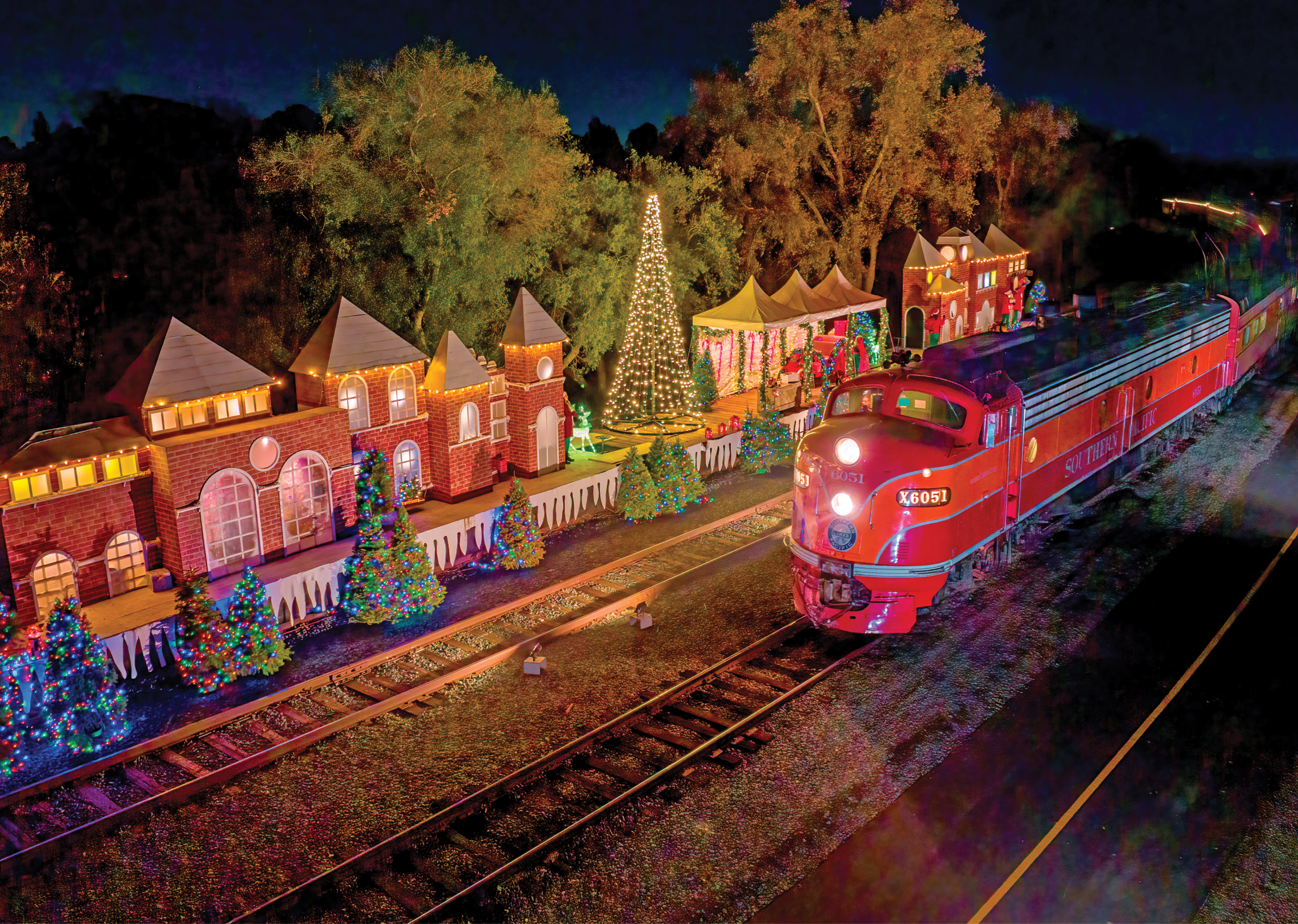 Night Time photograph of the polar express train passing through a station all decked out in Christmas lights