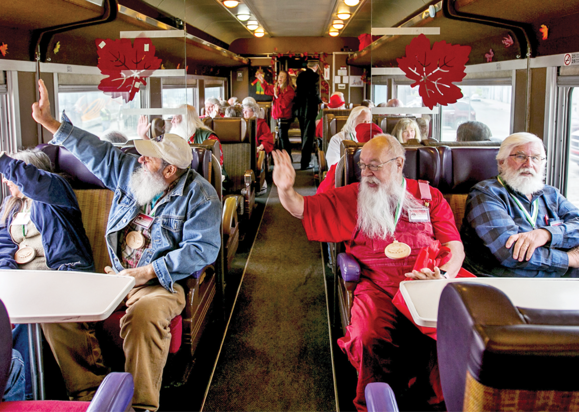 Inside shot of the North pole express train with a bunch of older people sitting inside and wavin out