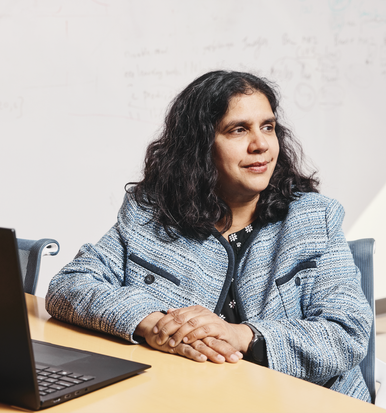 Damini sitting at a table working on a laptop