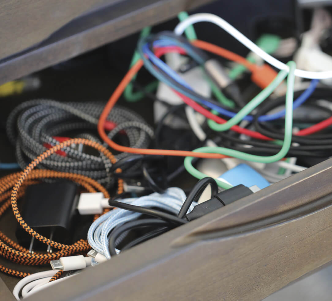 An open drawer filled with different color cables, all intertwined.
