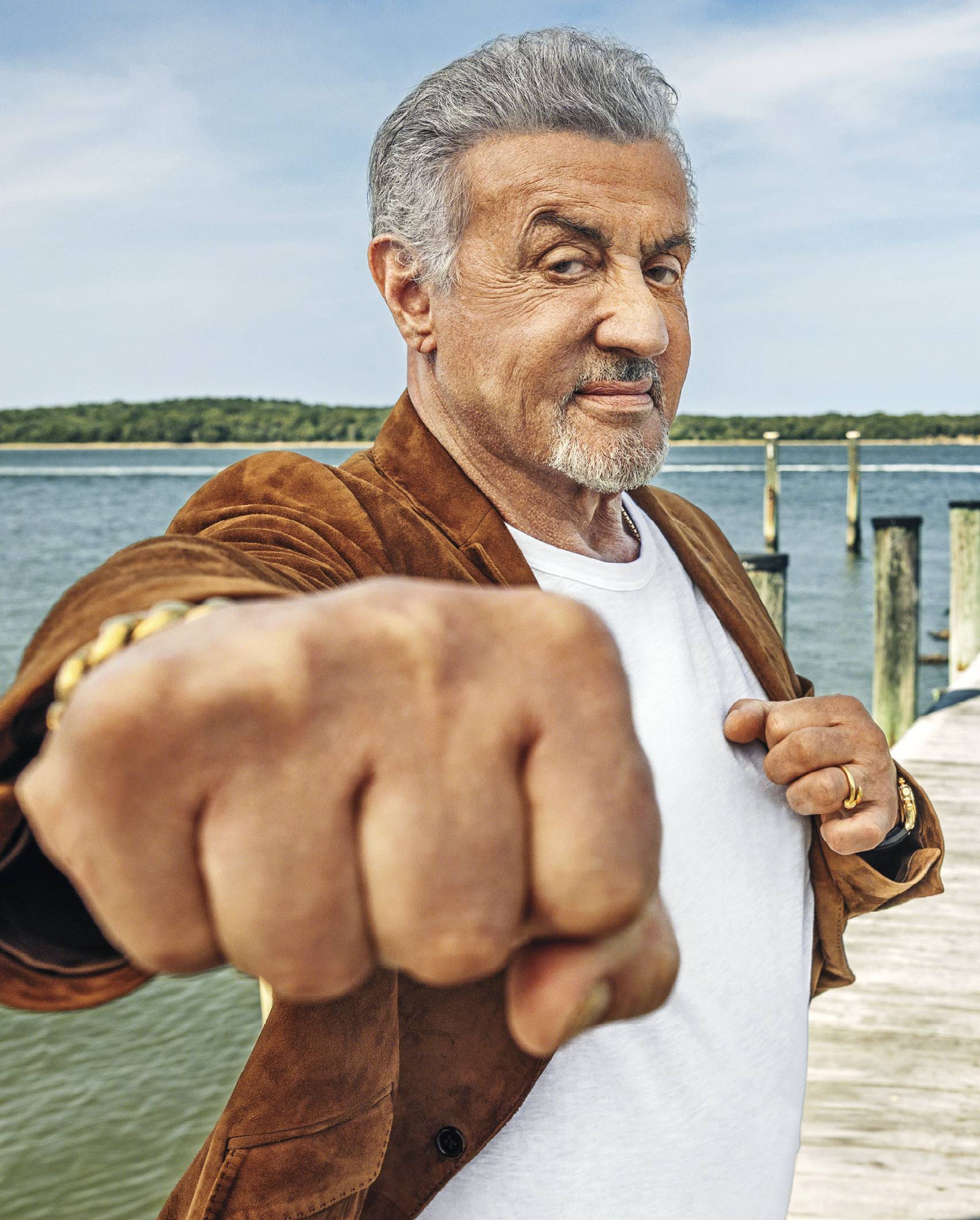 Photograph of Stallone making a fist and pointing it at the camera, smiling.