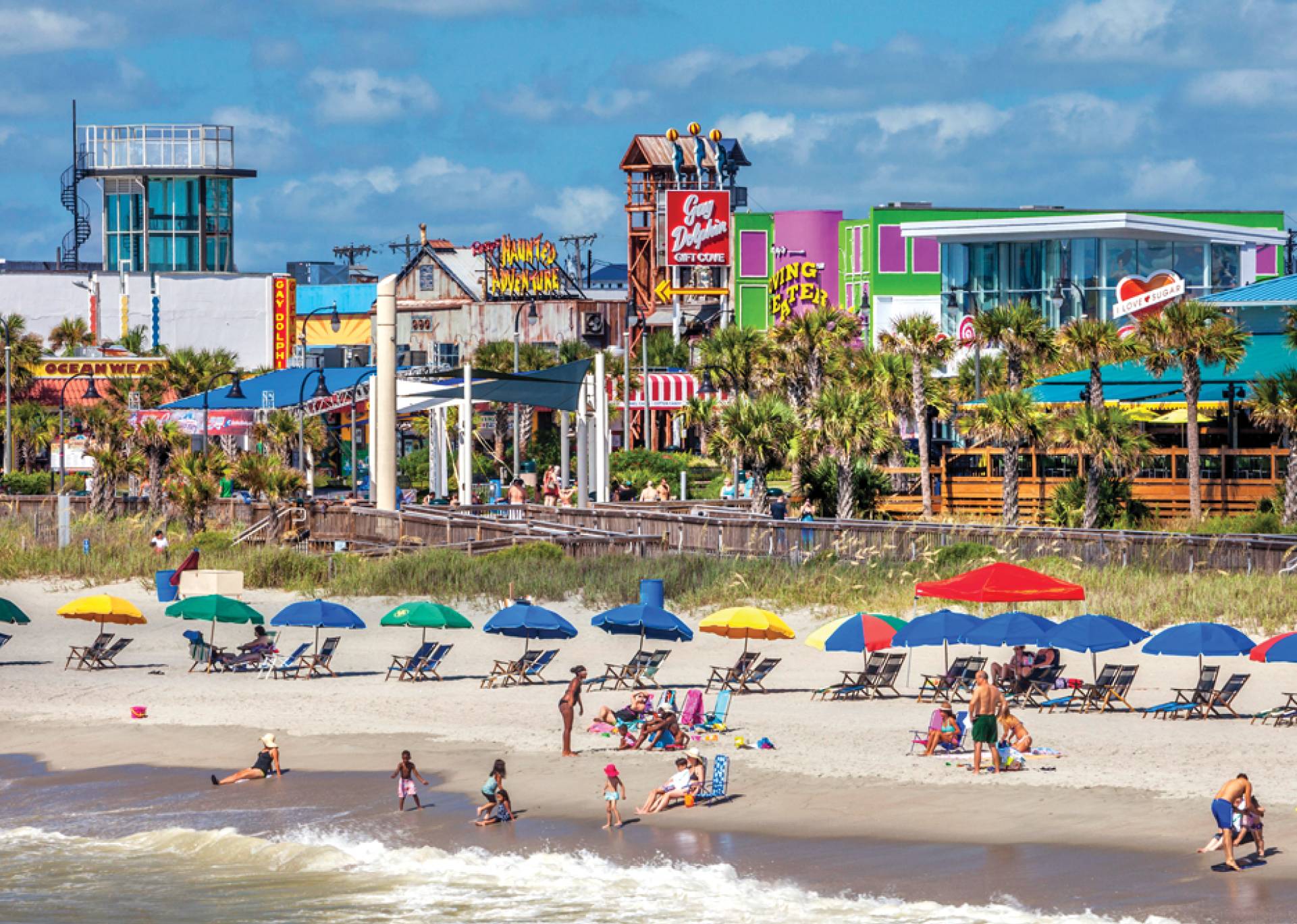 Image of the beachfront of Myrtle Beach with people sitting under beach umbrellas and the view of the skyline behind